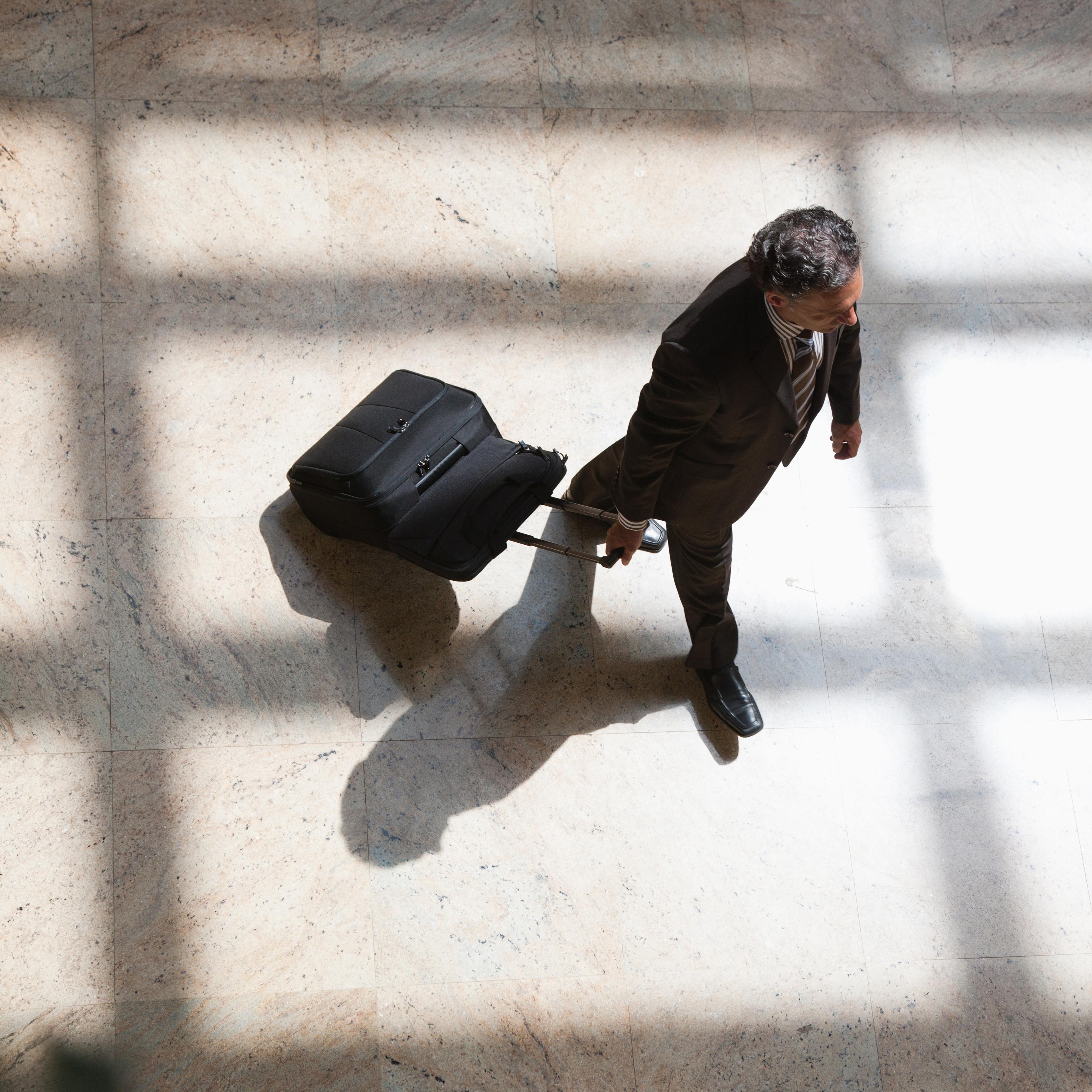Businessman pulling rolling suitcase