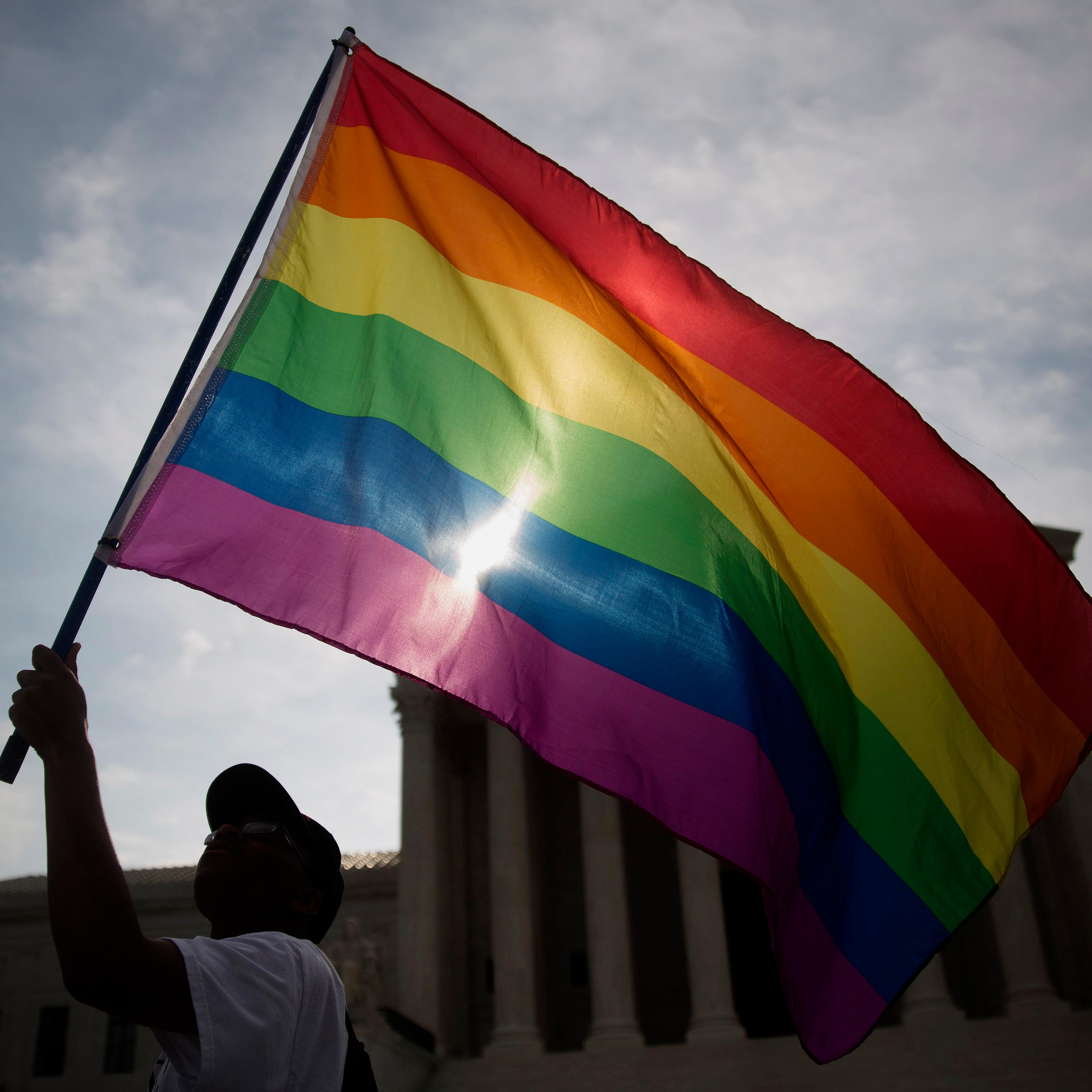 Carlos McKnight, from Washington, D.C., waves a rainbow colored flag outside the U.S. Supreme Court in Washington, D.C., U.S., on Friday, June 26, 2015.