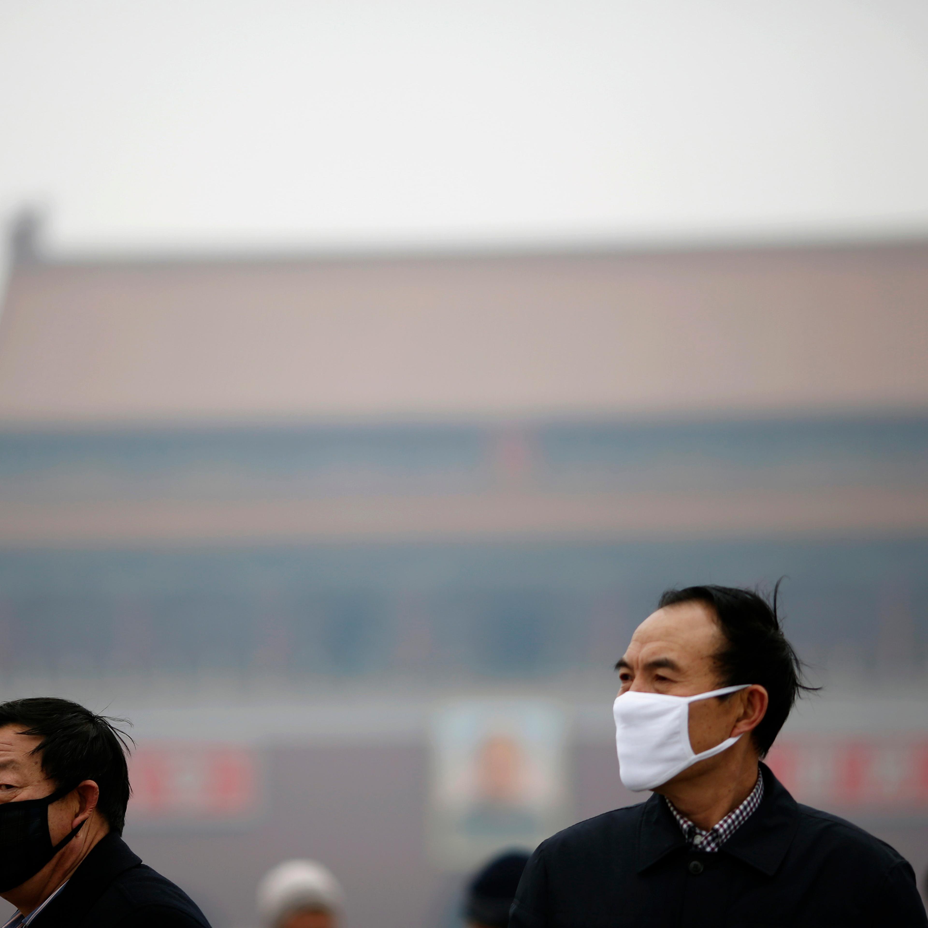 People wearing masks are seen on a hazy day at Tiananmen Square in Beijing