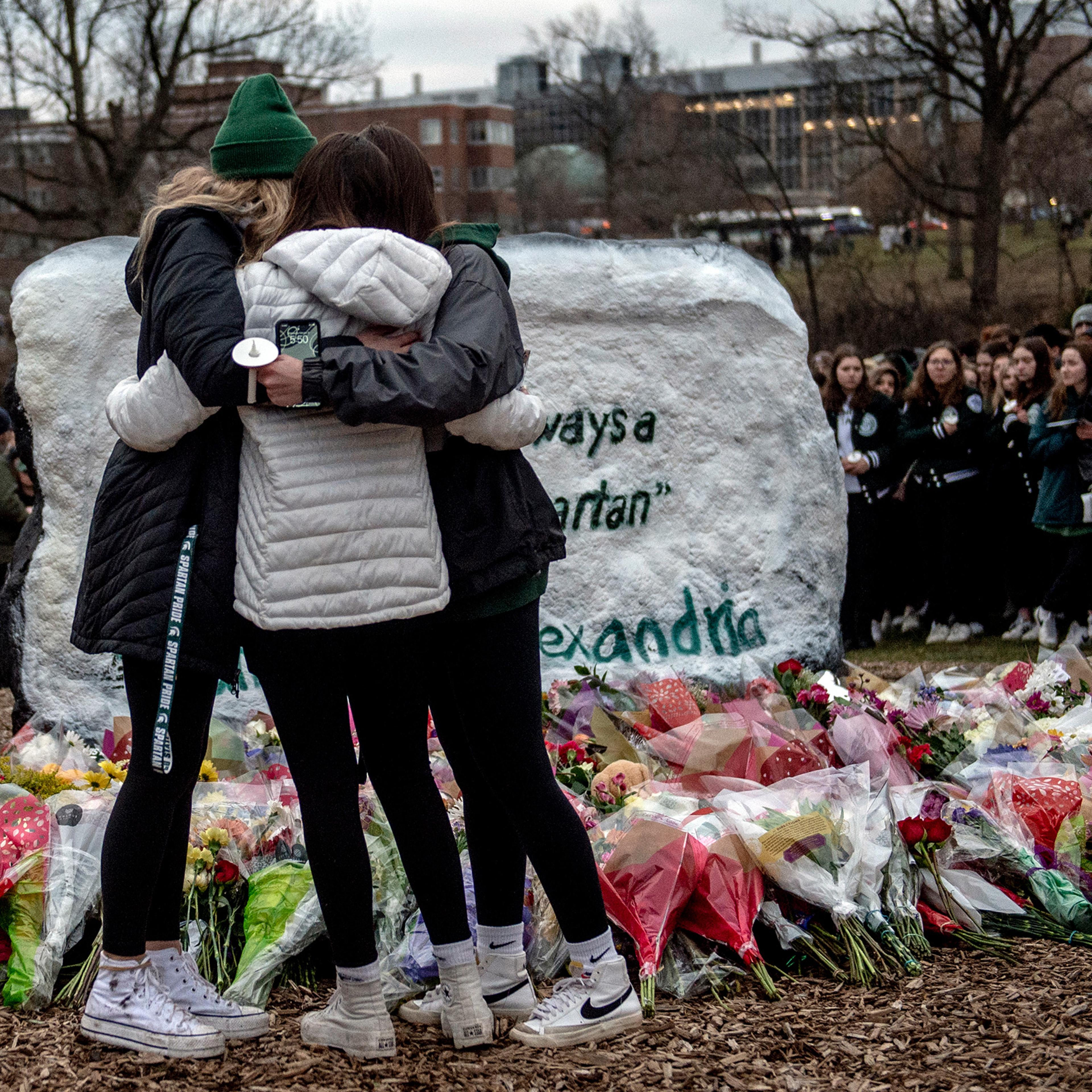 Michigan State freshman twins Lauren Schelling and Olivia Schelling, both 19, embrace their friend Brooke Goudreau, an 18-year-old MSU freshman from Southgate, while coping with the loss of three students at The Rock, a popular college landmark where a makeshift memorial continues to grow with flowers and keepsakes on Feb. 15 at Michigan State University in East Lansing, Mich. Two days ago on the evening of Feb. 13, three students were killed and others injured during a mass shooting on the campus.