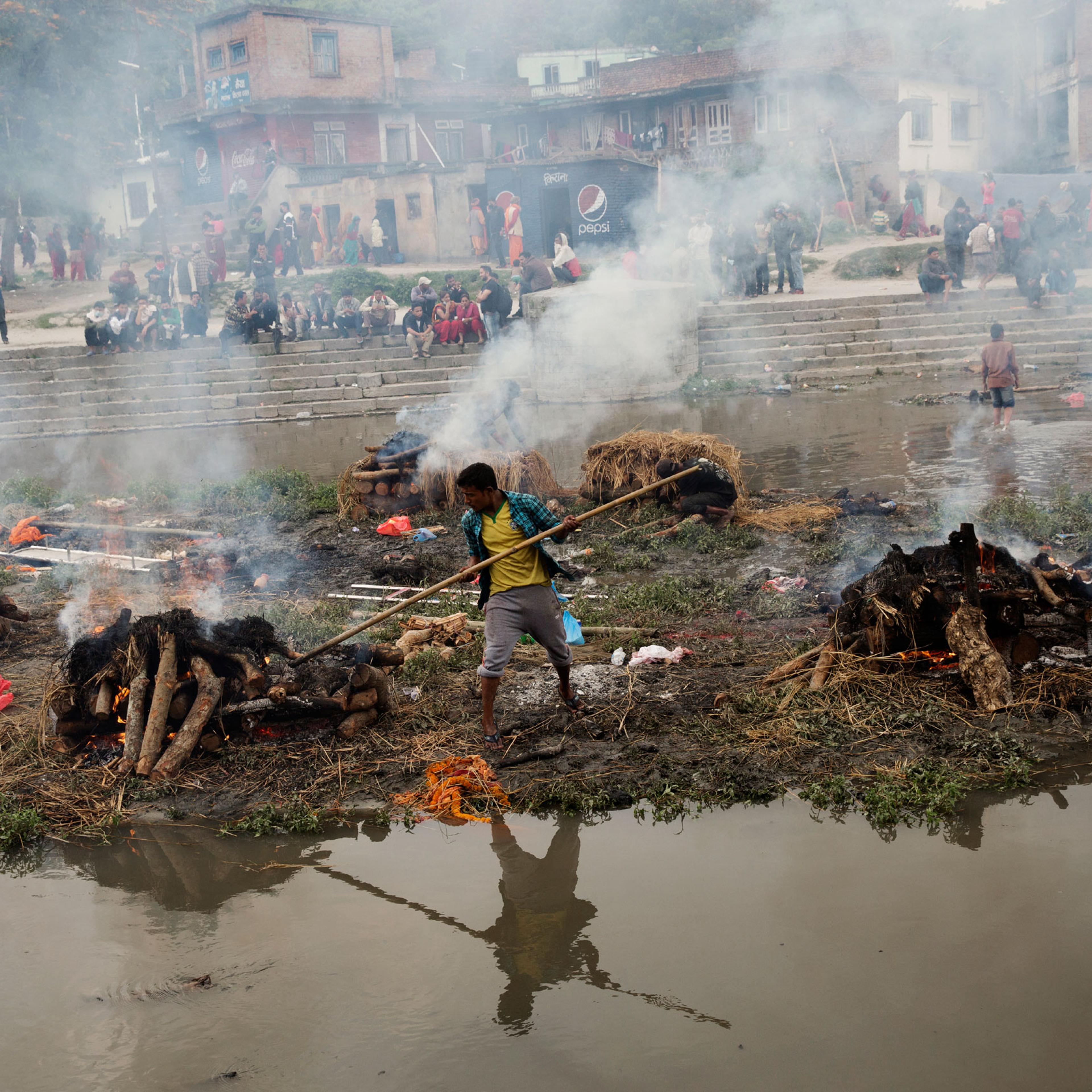 A Hindu Nepali man tends to a funeral pyre built for a person killed in the earthquake in Nepal, on the river in Kathmandu, Nepal on April. 27, 2015. Nepal had a severe earthquake on April 25th. Photo by Adam Ferguson for Time