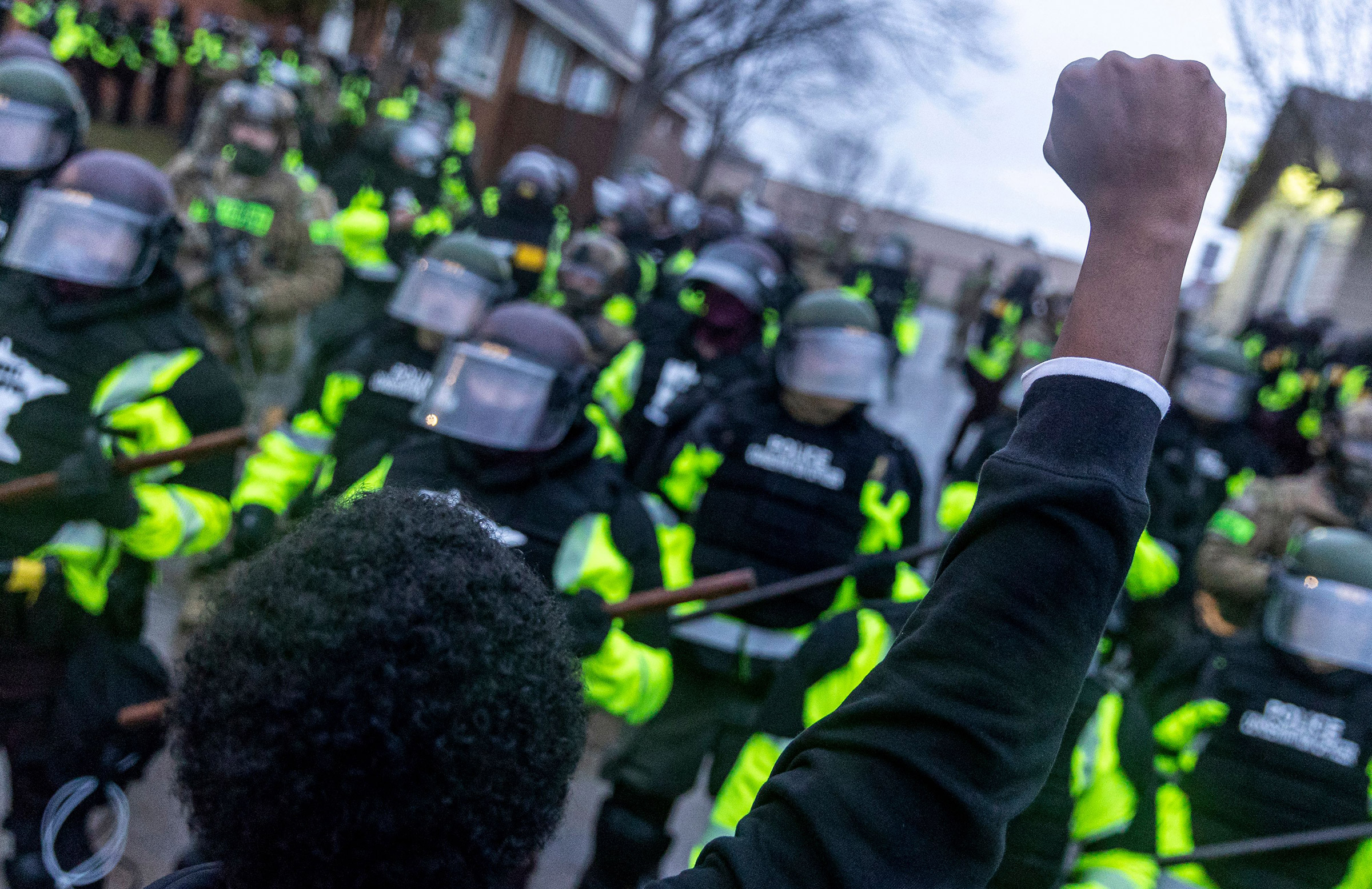 A man raises his fist as he faces the Minnesota State Troopers standing guard outside the Brooklyn Center Police Station after a police officer shot and killed 20-year-old Daunte Wright during a traffic stop in Brooklyn Center, Minneapolis, Minnesota on April 12, 2021. 