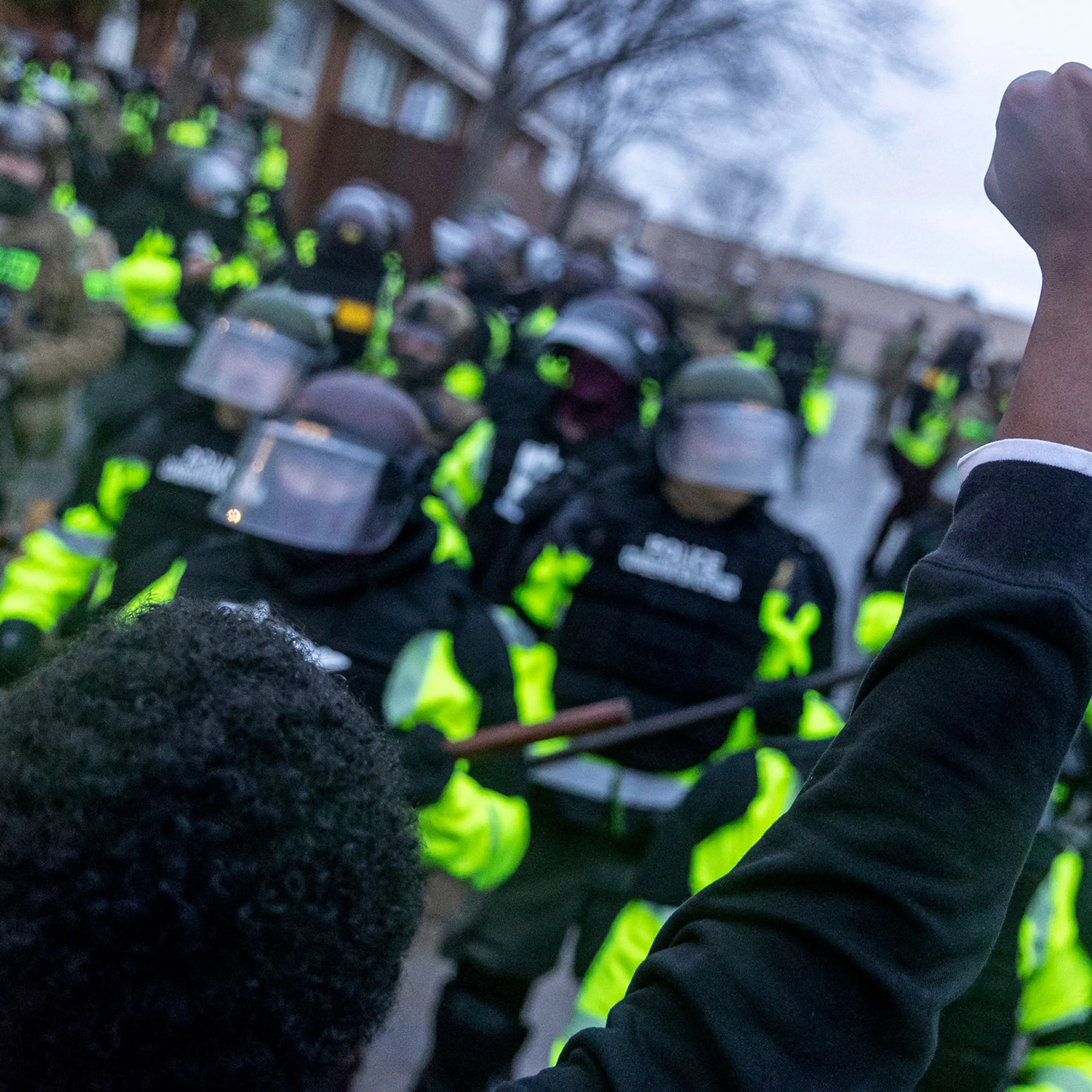 A man raises his fist as he faces the Minnesota State Troopers standing guard outside the Brooklyn Center Police Station after a police officer shot and killed 20-year-old Daunte Wright during a traffic stop in Brooklyn Center, Minneapolis, Minnesota on April 12, 2021.
