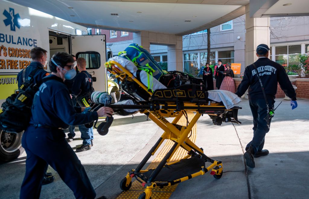 Christmas carol singers look on and take a break from a Christmas party as paramedics walk into the Goodwin House senior living community center in Arlington, Virginia, during the coronavirus pandemic on December 10, 2020.
