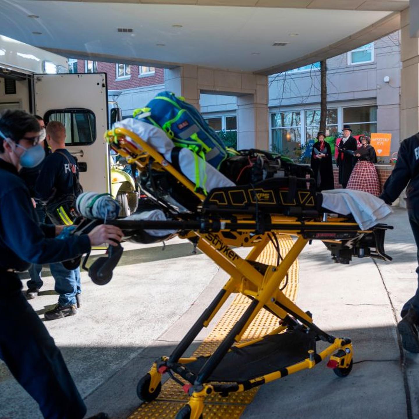 Christmas carol singers look on and take a break from a Christmas party as paramedics walk into the Goodwin House senior living community center in Arlington, Virginia, during the coronavirus pandemic on December 10, 2020.