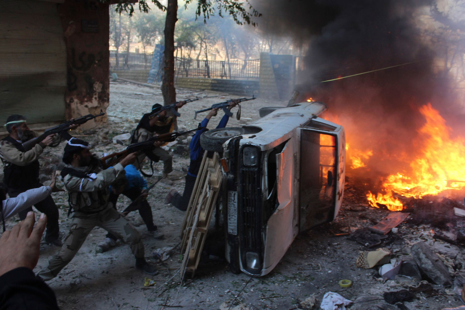 Free Syrian Army fighters take positions behind a damaged car as they fire their weapons during an offensive against forces loyal to Syria's President Bashar al-Assad in Aleppo's Salaheddine neighbourhood