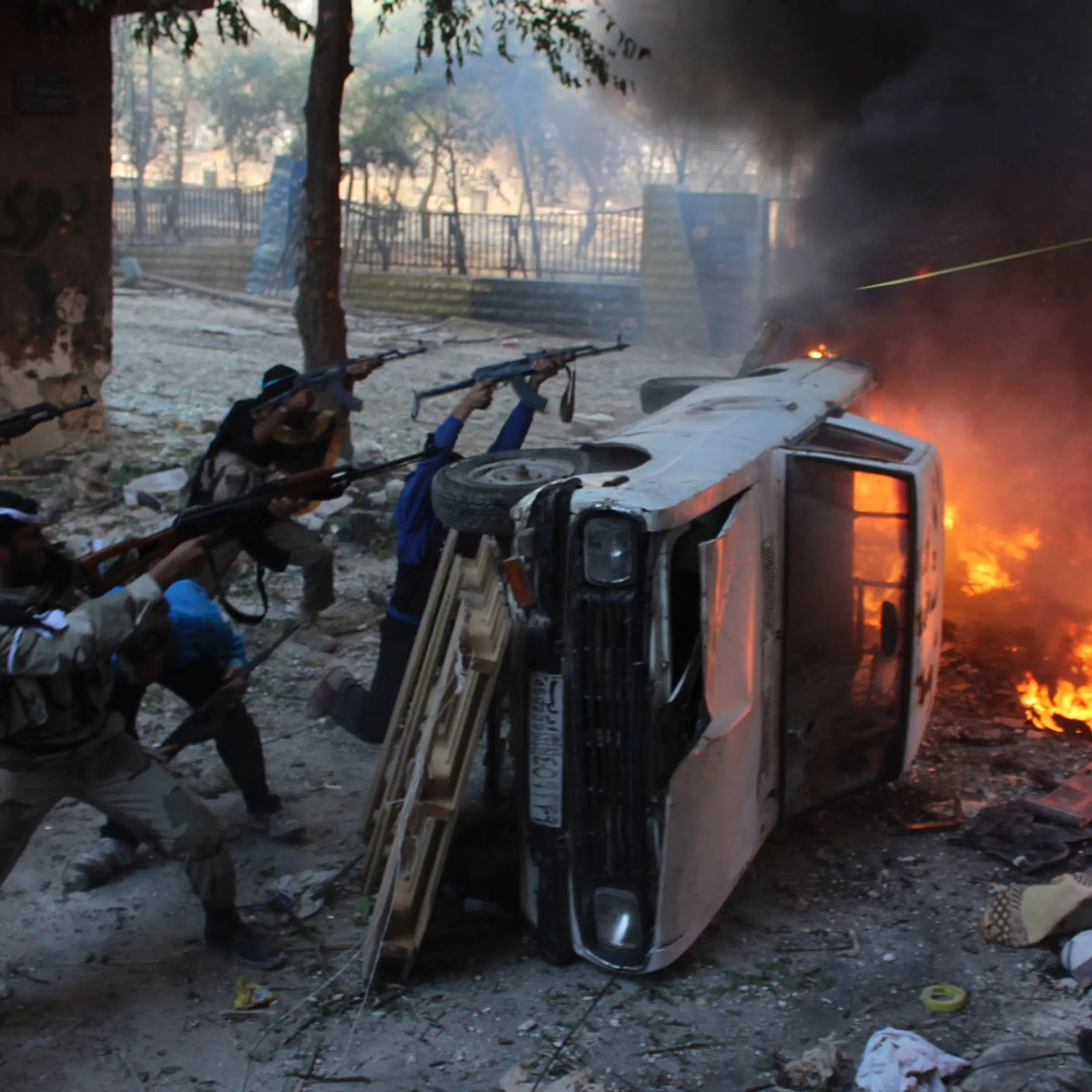 Free Syrian Army fighters take positions behind a damaged car as they fire their weapons during an offensive against forces loyal to Syria's President Bashar al-Assad in Aleppo's Salaheddine neighbourhood