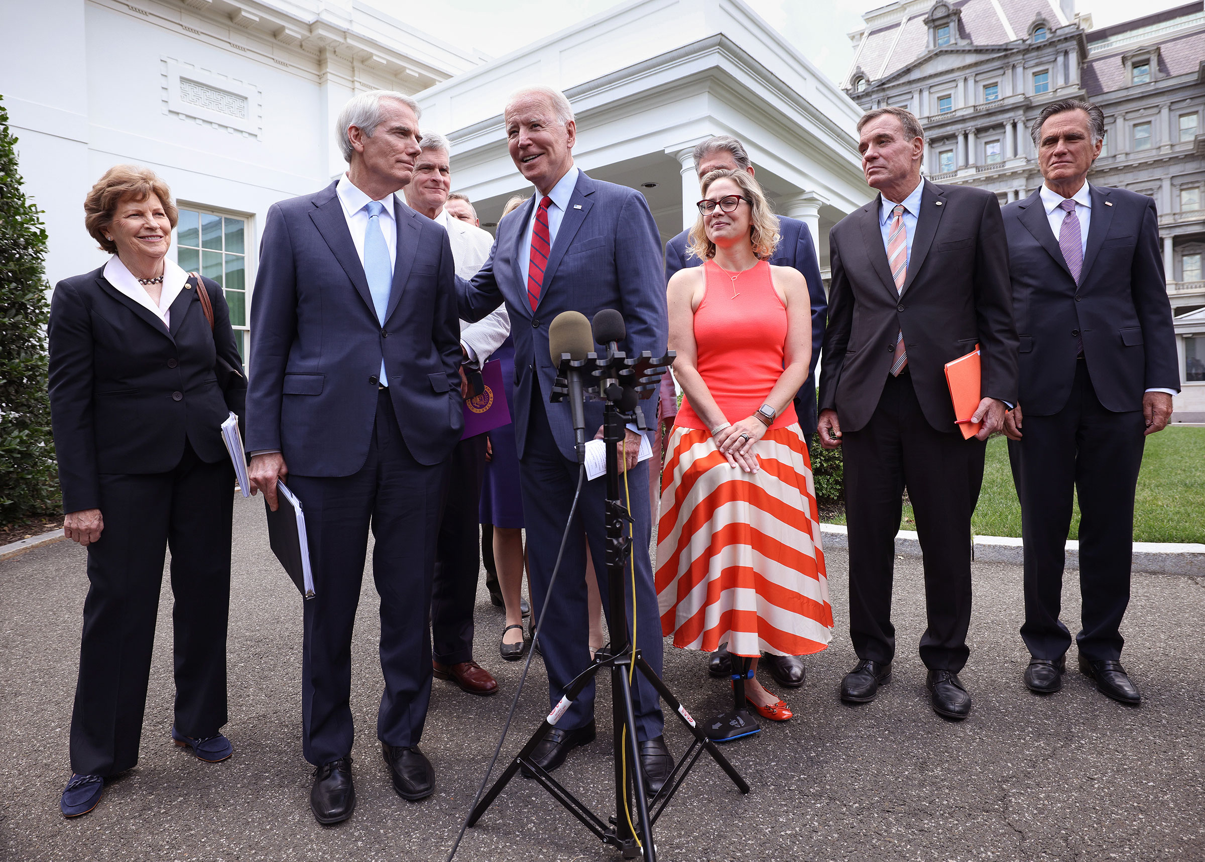 President Joe Biden (C), joined by from left to right, Sen Jeanne Shaheen (D-NH), Sen. Rob Portman (R-OH), Sen Bill Cassidy (R-LA), Sen. Kyrsten Sinema (D-AZ), Sen. Mark Warner (D-VA) and Sen Mitt Romney (R-UT), speaks after the bipartisan group of Senat