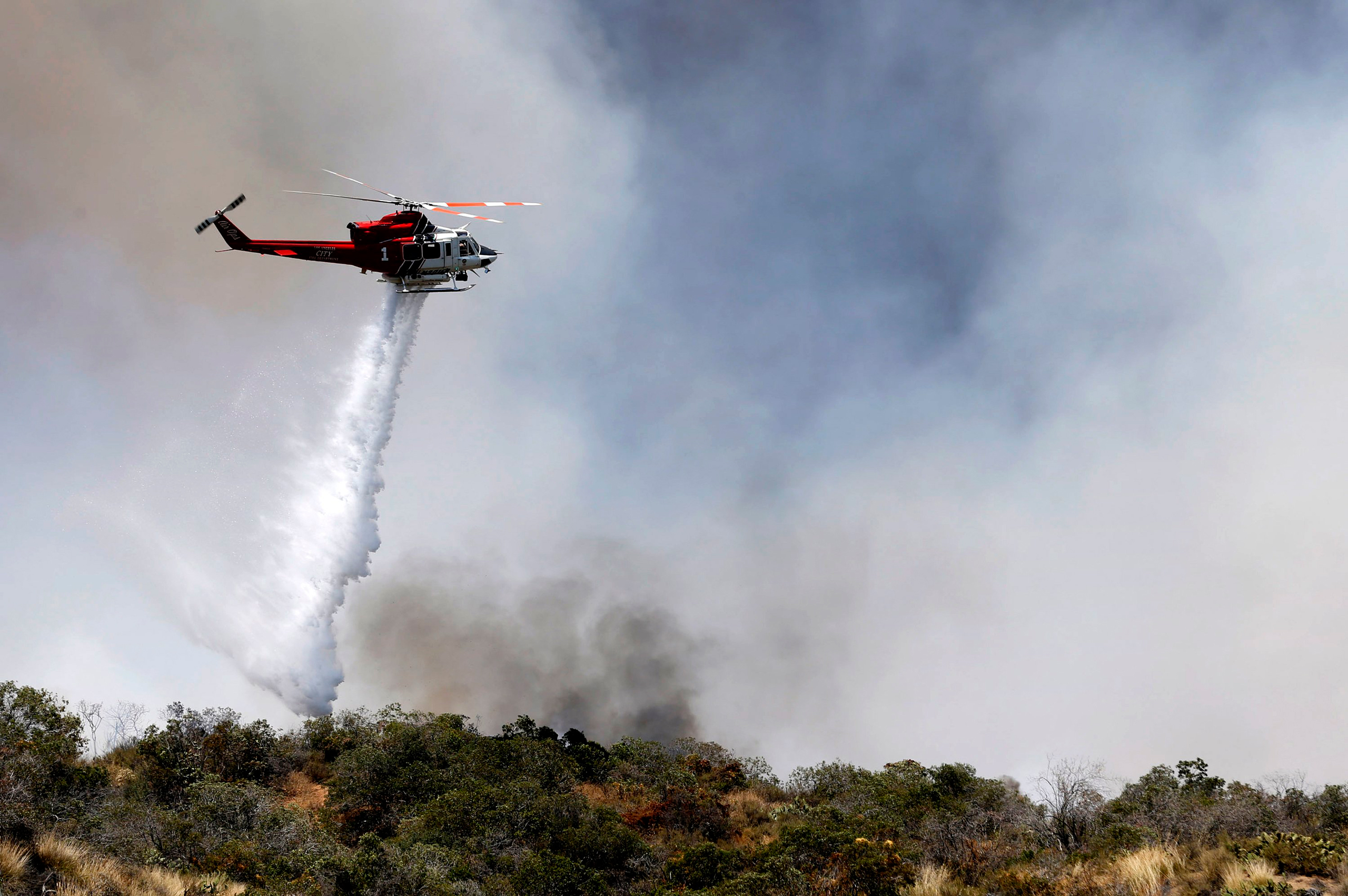 A firefighting helicopter makes a water drop over a wildfire just north of Azusa, Calif., Monday, June 20, 2016. Two fires have erupted in the San Gabriel Mountains northeast of Los Angeles amid withering heat. The first fire reported Monday was near Mor