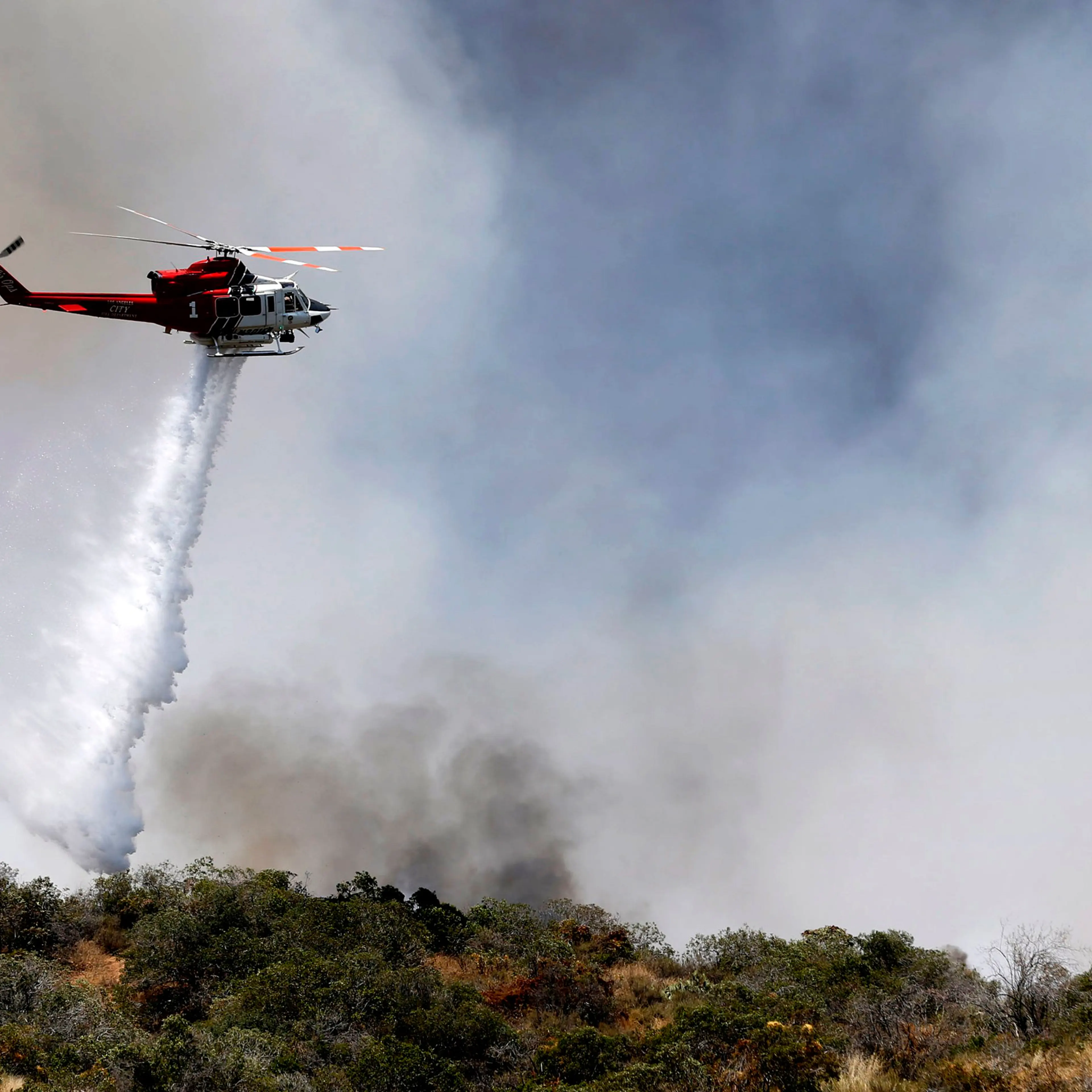 A firefighting helicopter makes a water drop over a wildfire just north of Azusa, Calif., Monday, June 20, 2016. Two fires have erupted in the San Gabriel Mountains northeast of Los Angeles amid withering heat. The first fire reported Monday was near Mor