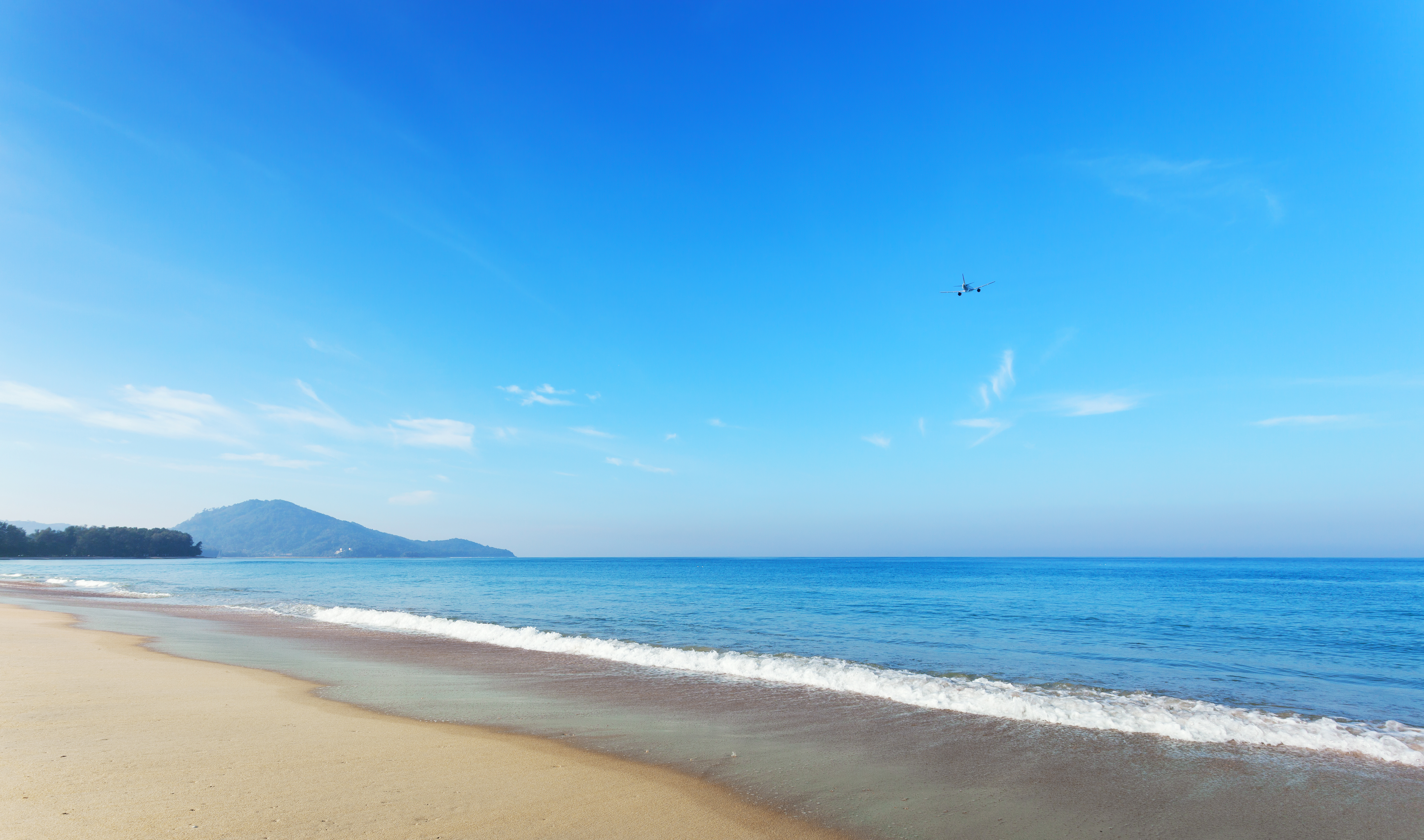 Tropical andaman seascape scenic off mai khao beach and wave crashing on sandy shore in phuket thailand with airplane takes off on sky in summer season.