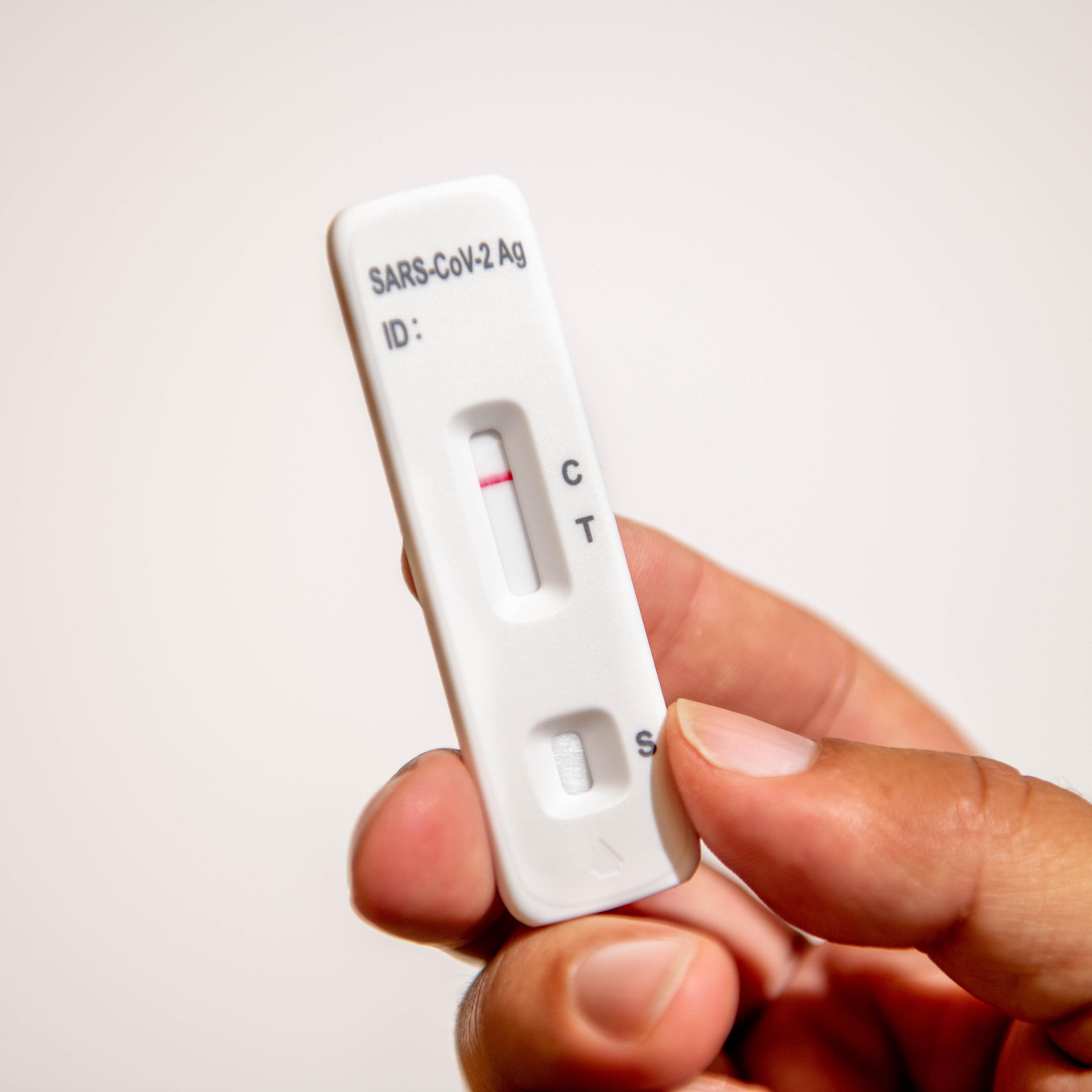 Male hand holding a negative SARS-Covid test against white background
