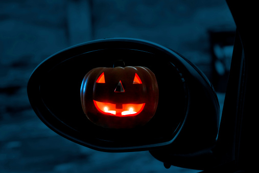 Jack o' lantern in rear view mirror of car