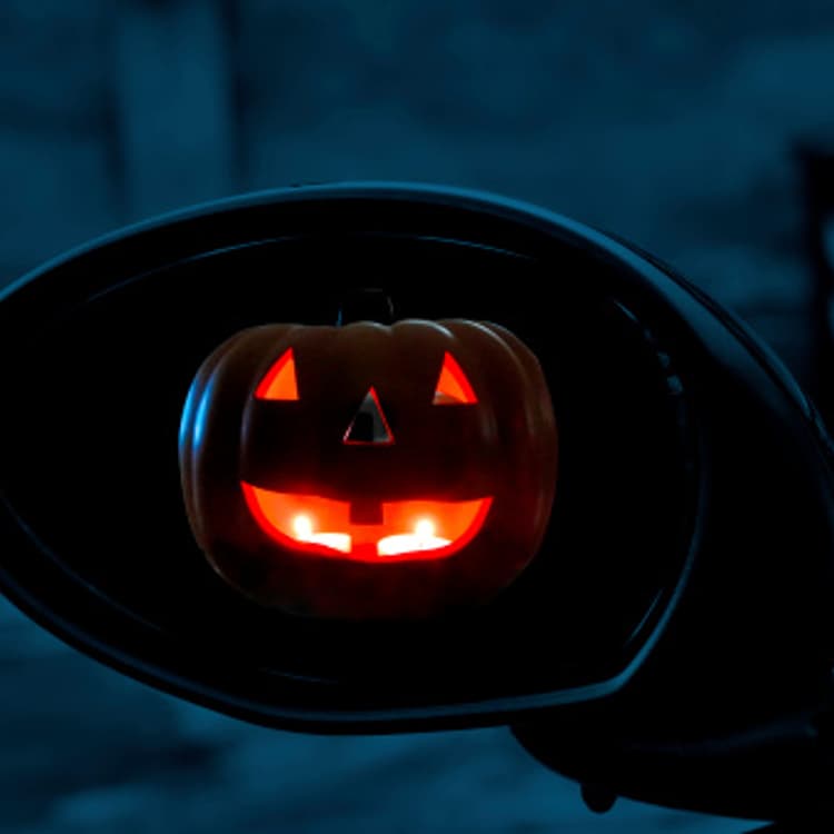 Jack o' lantern in rear view mirror of car