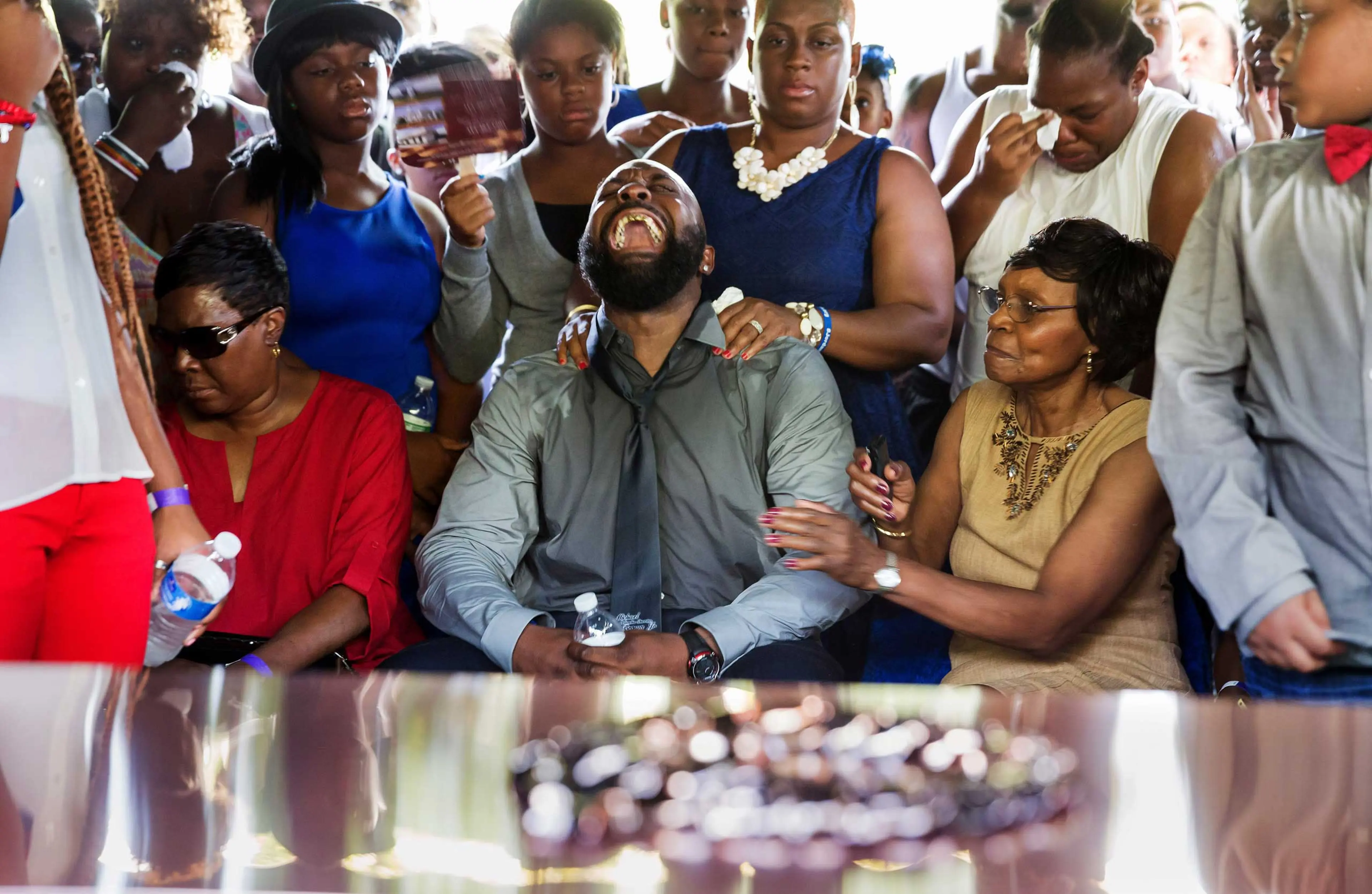 Michael Brown Sr, yells out as his son's casket is lowered into the ground at St. Peter's Cemetery in St. Louis