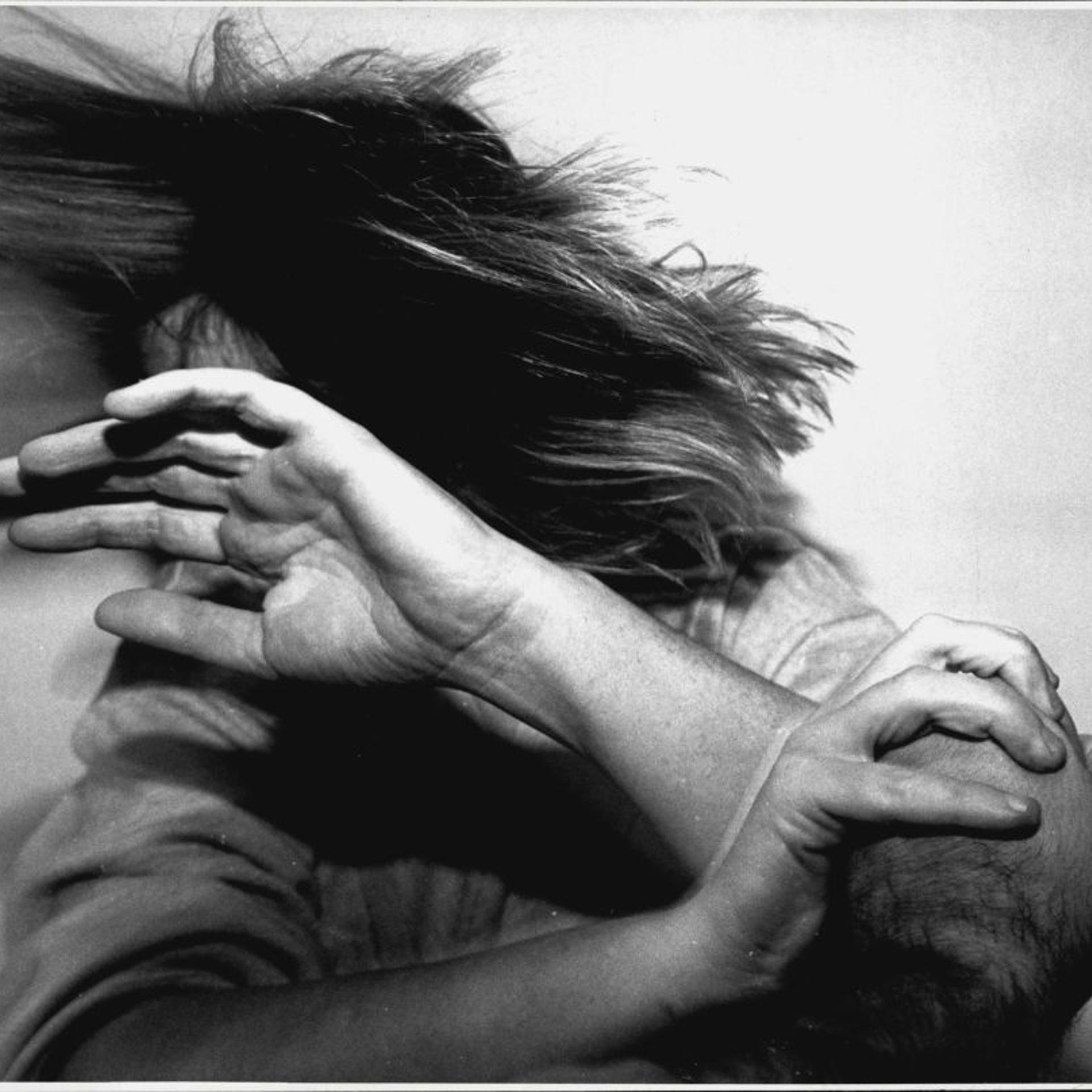 A black and white photo shows a woman turning away from a man's fist.