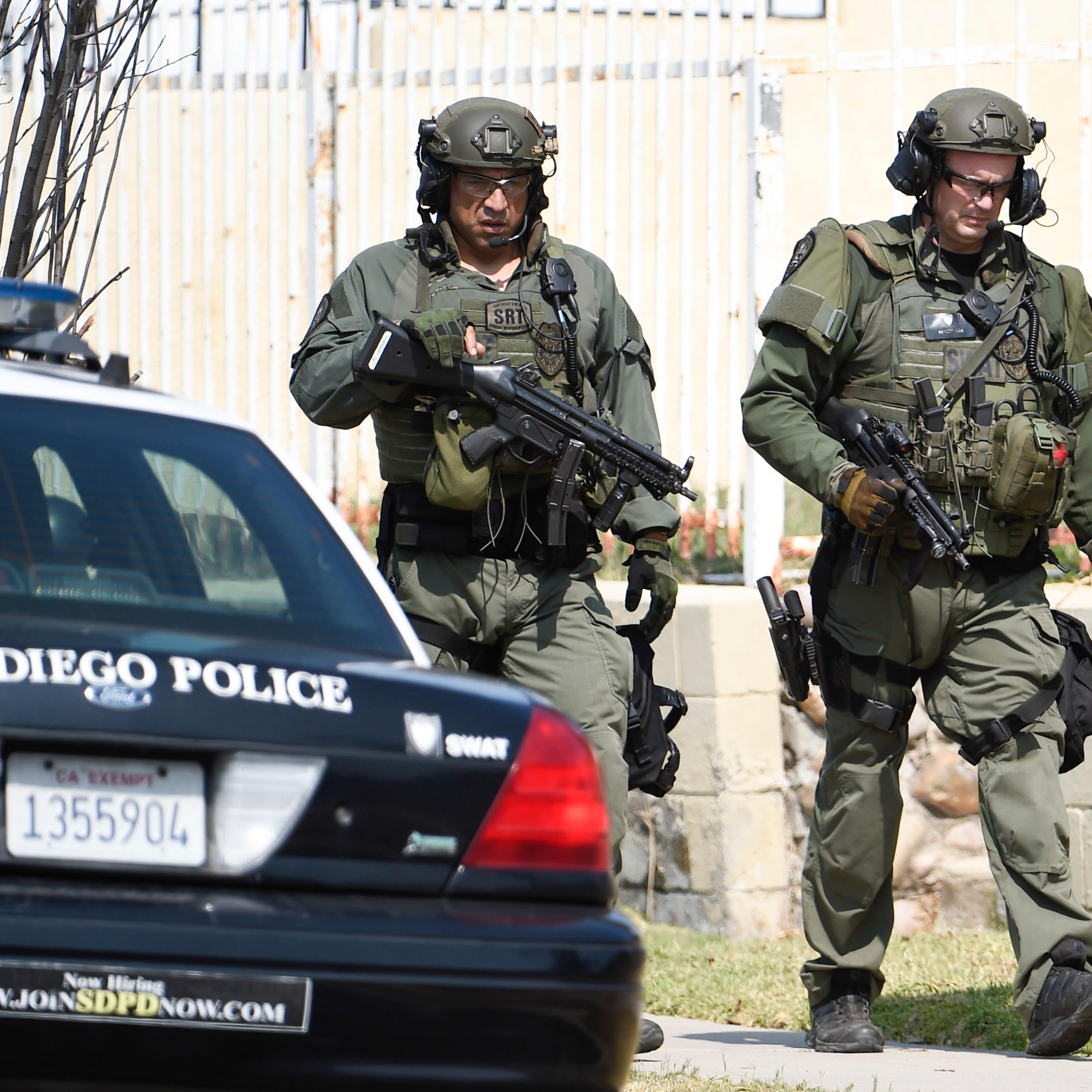 San Diego Police SWAT officers walk down the street after entering a house with a possible suspect inside, on July 29, 2016, in San Diego.