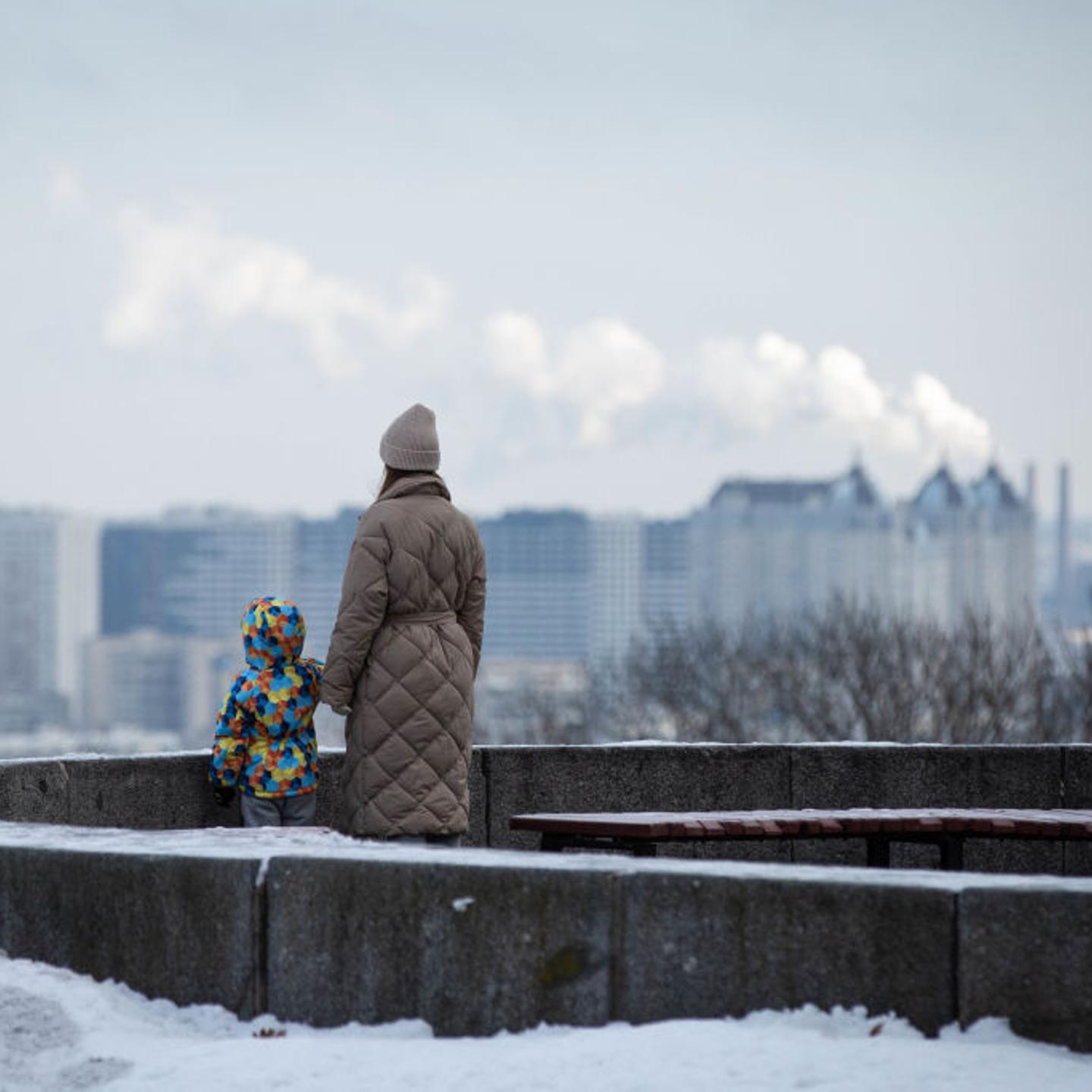 A woman and a child look at the left-bank districts of Kyiv