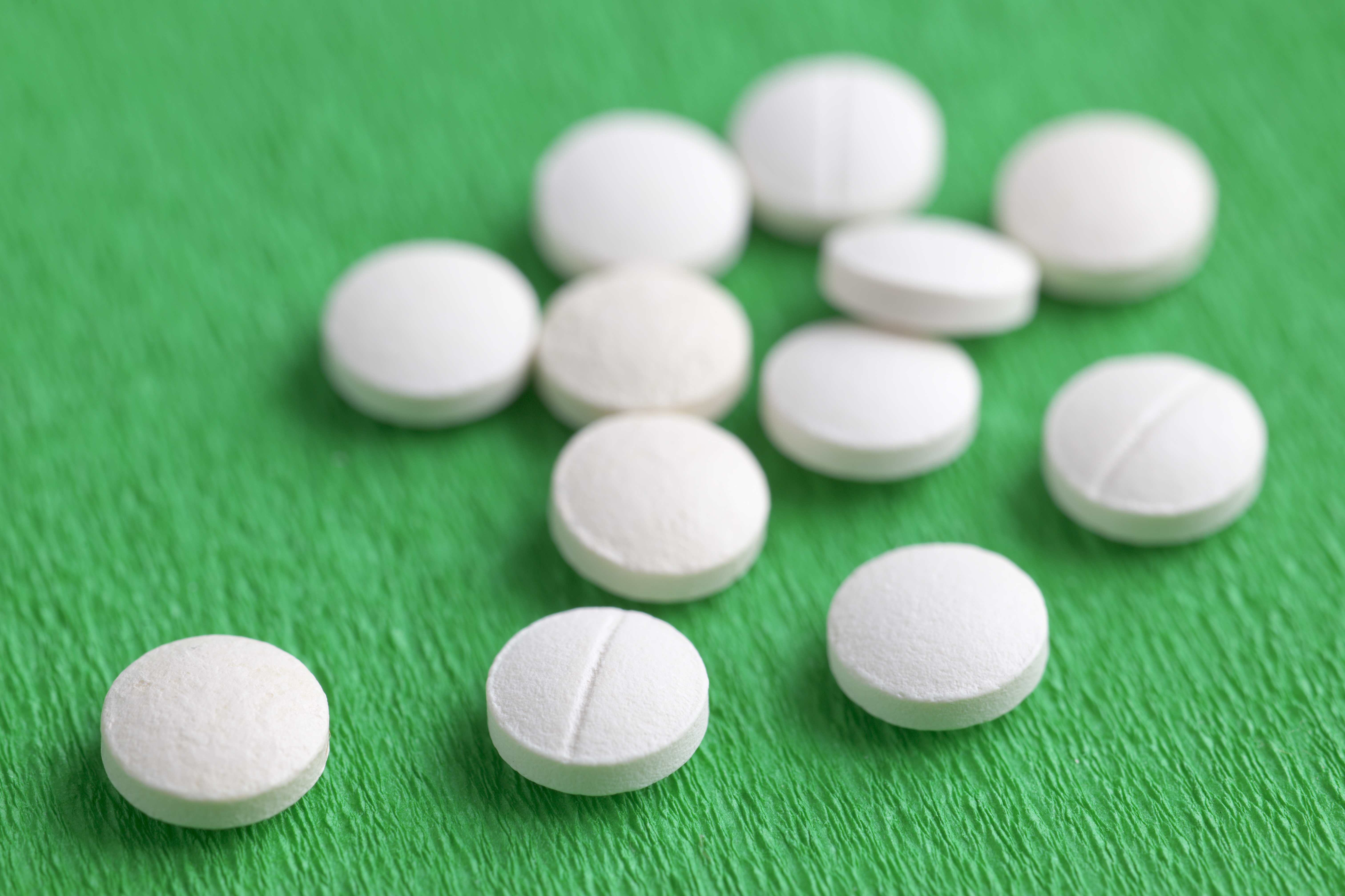 White Melatonin Natural Medicine Sleeping Pills on Green Backgro