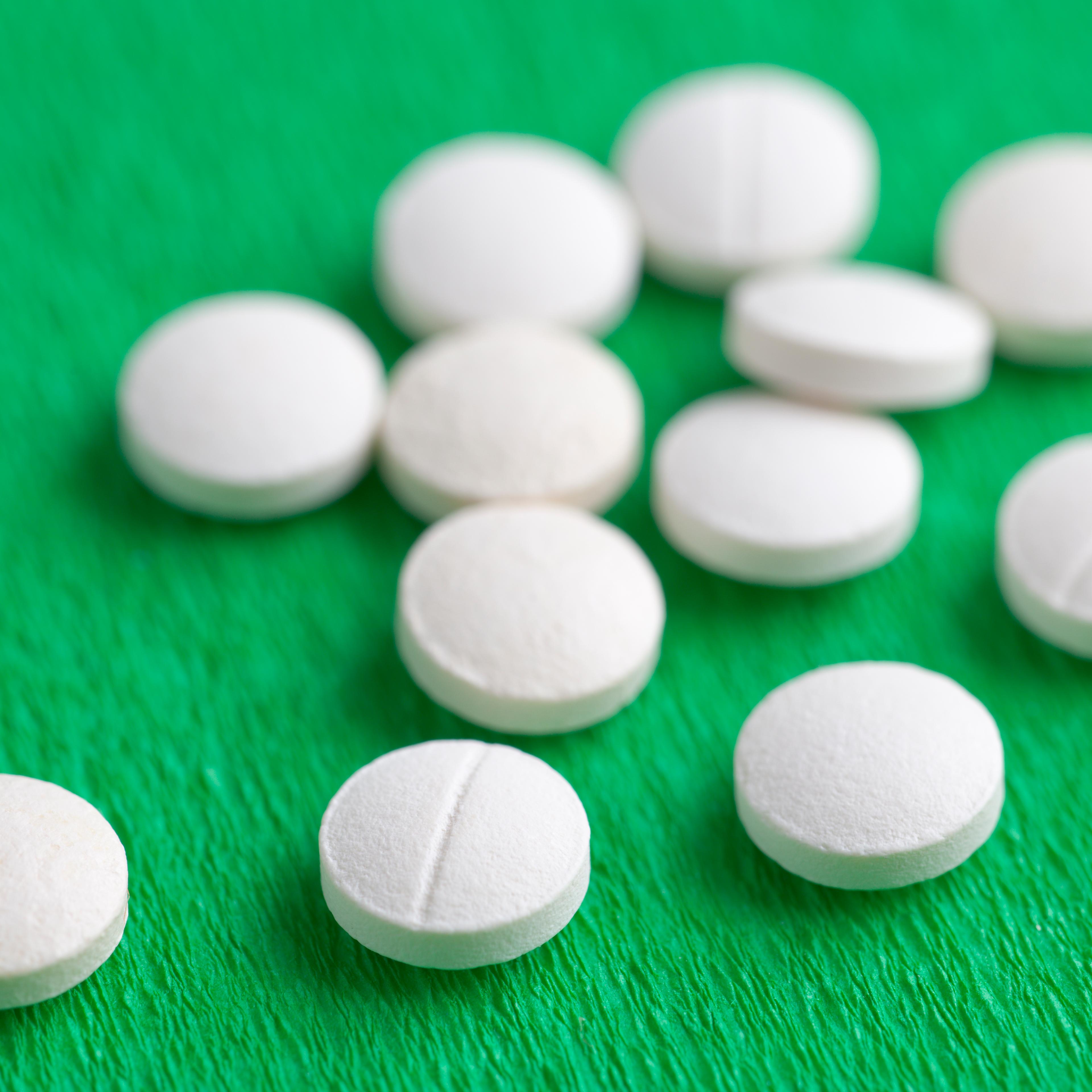 White Melatonin Natural Medicine Sleeping Pills on Green Backgro