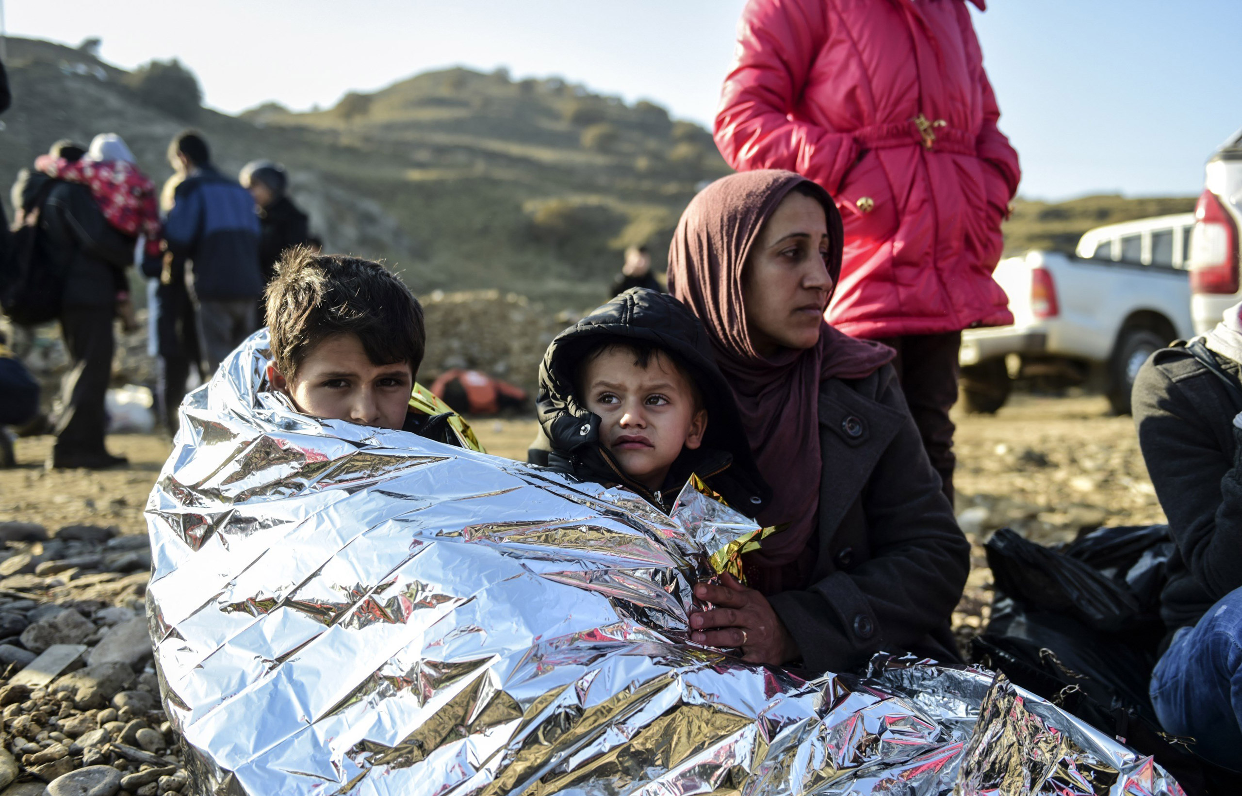 A Syrian family waits after arriving on the Greek island of Lesbos along with other migrants and refugees, on November 17, 2015, after crossing the Aegean Sea from Turkey. At least eight people drowned when a boat carrying migrants from Turkey sank off t