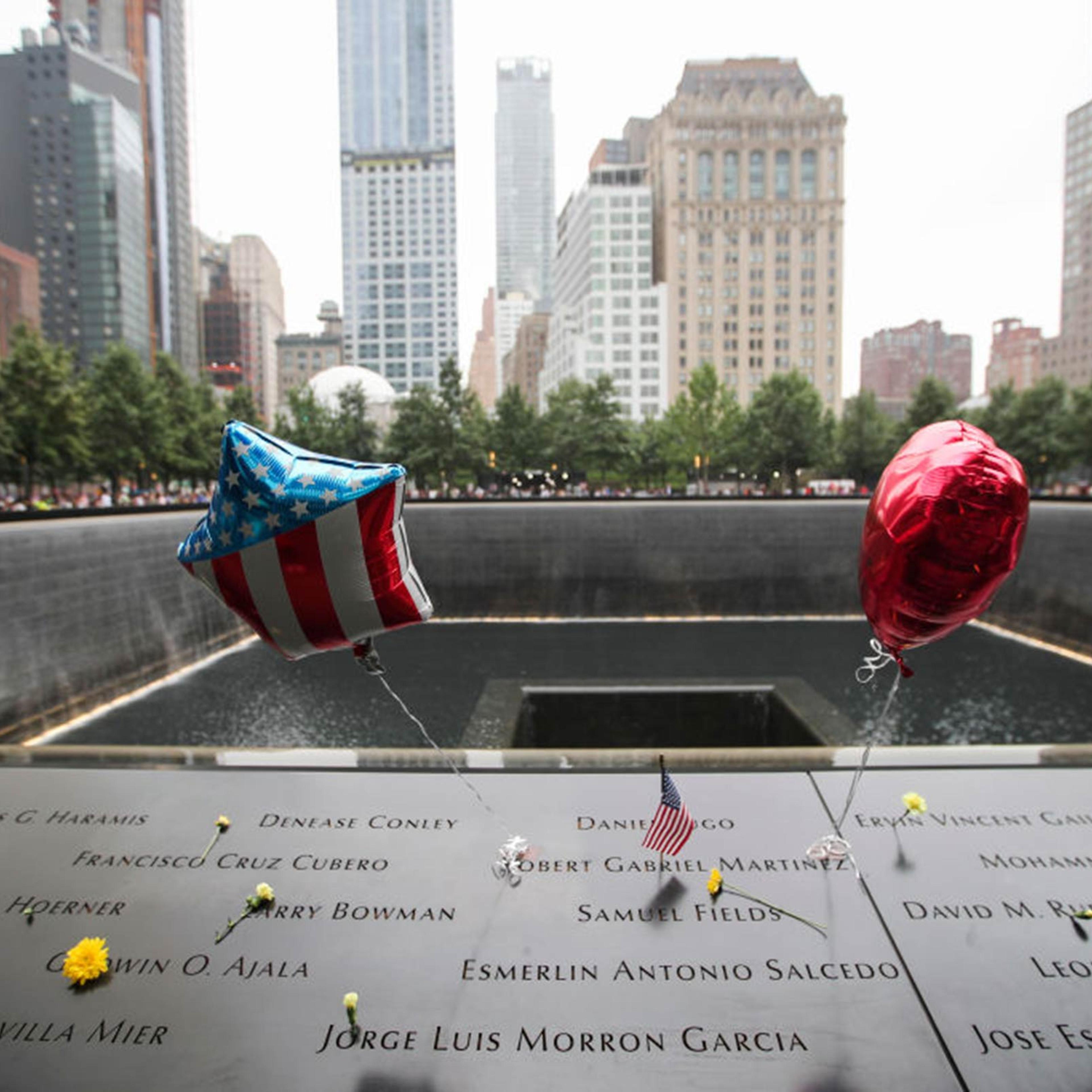 Flowers and balloons are placed on plates on which the names of 9/11 victims were inscribed around the South Pool at the 9/11 Memorial and Museum in New York City on Sept. 11, 2018.