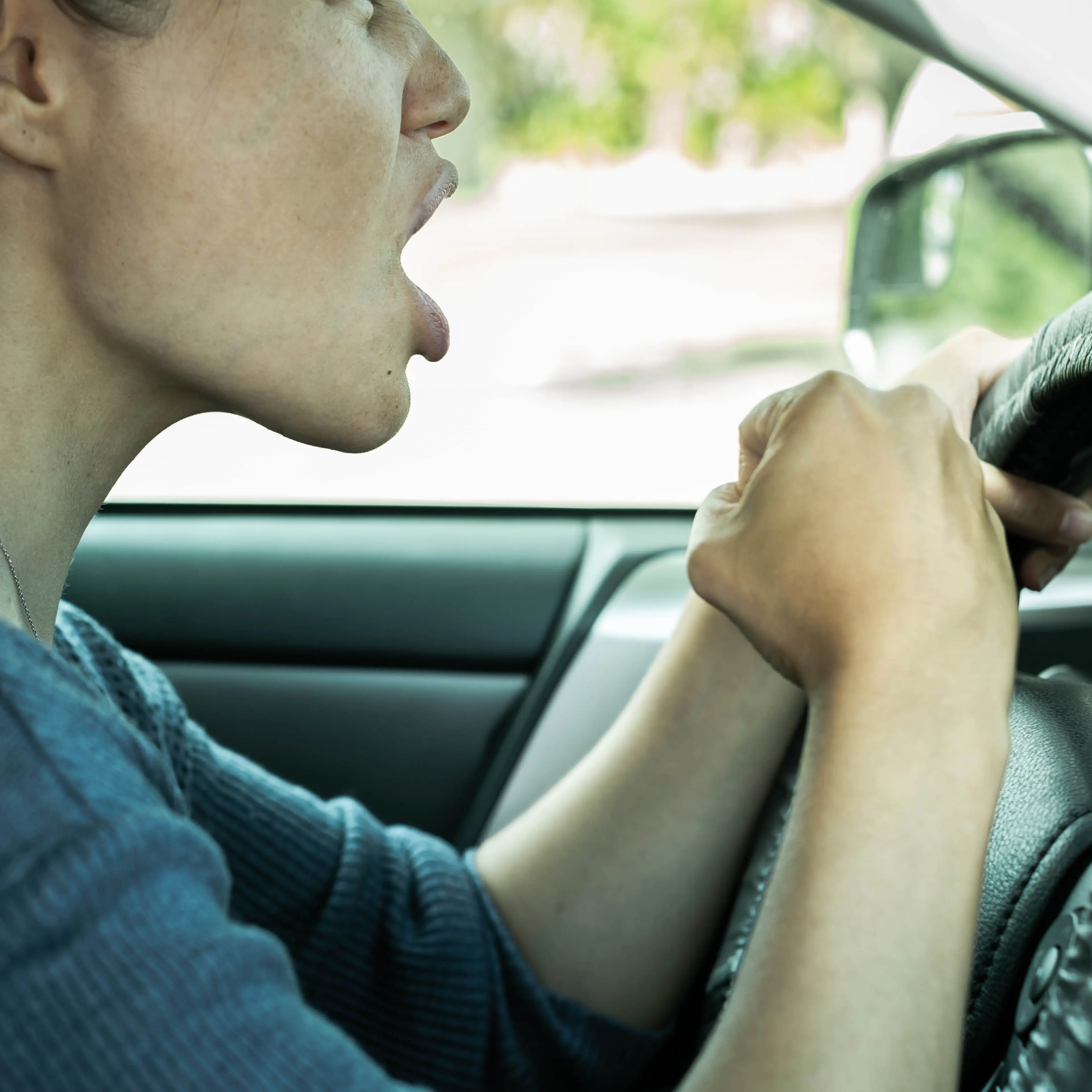 Road rage. Angry woman driving her car honking the horn and yelling.