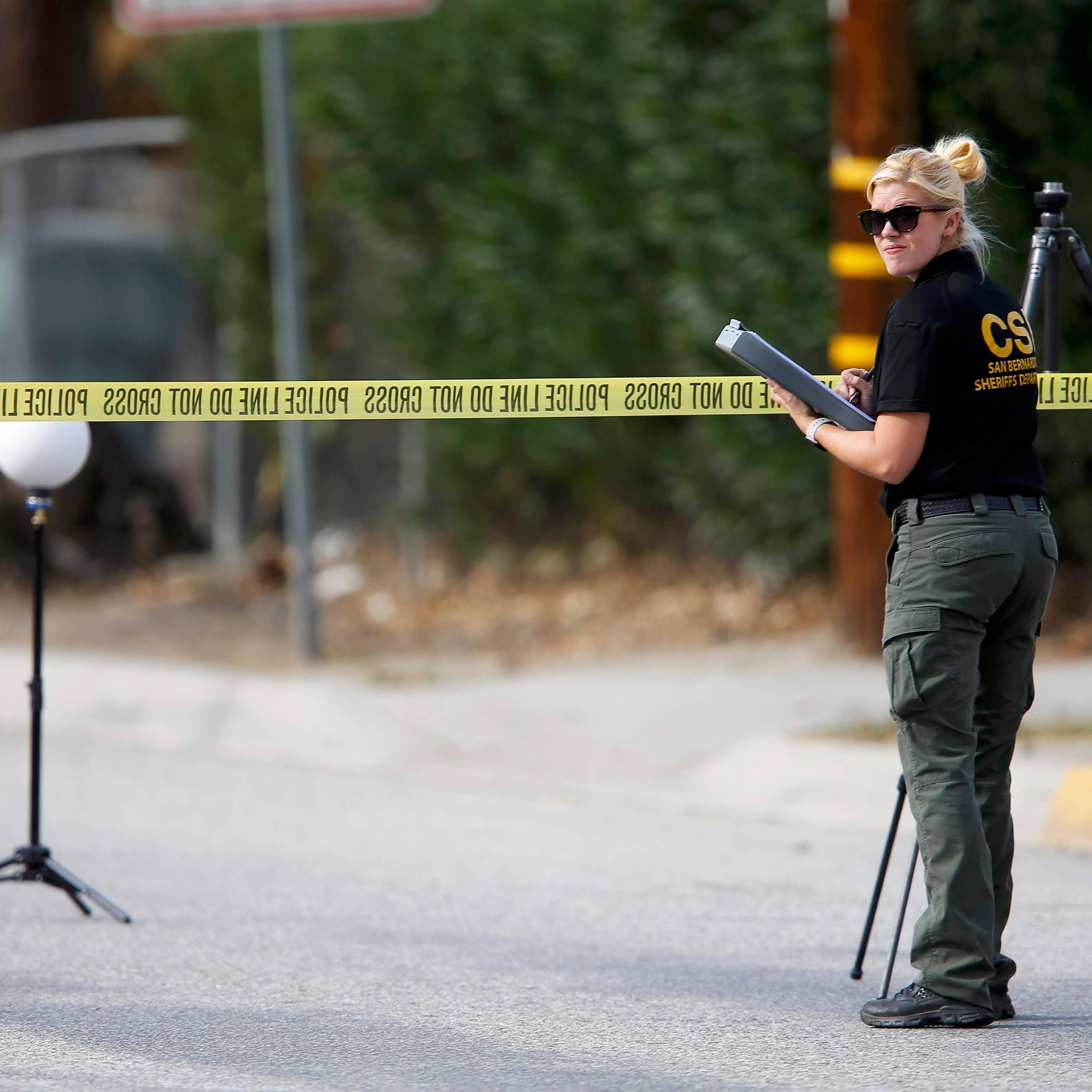 A Sheriff's Office Crime Scene Iinvestigator inspects the scene around an SUV where two suspects were shot by police following a mass shooting in San Bernardino
