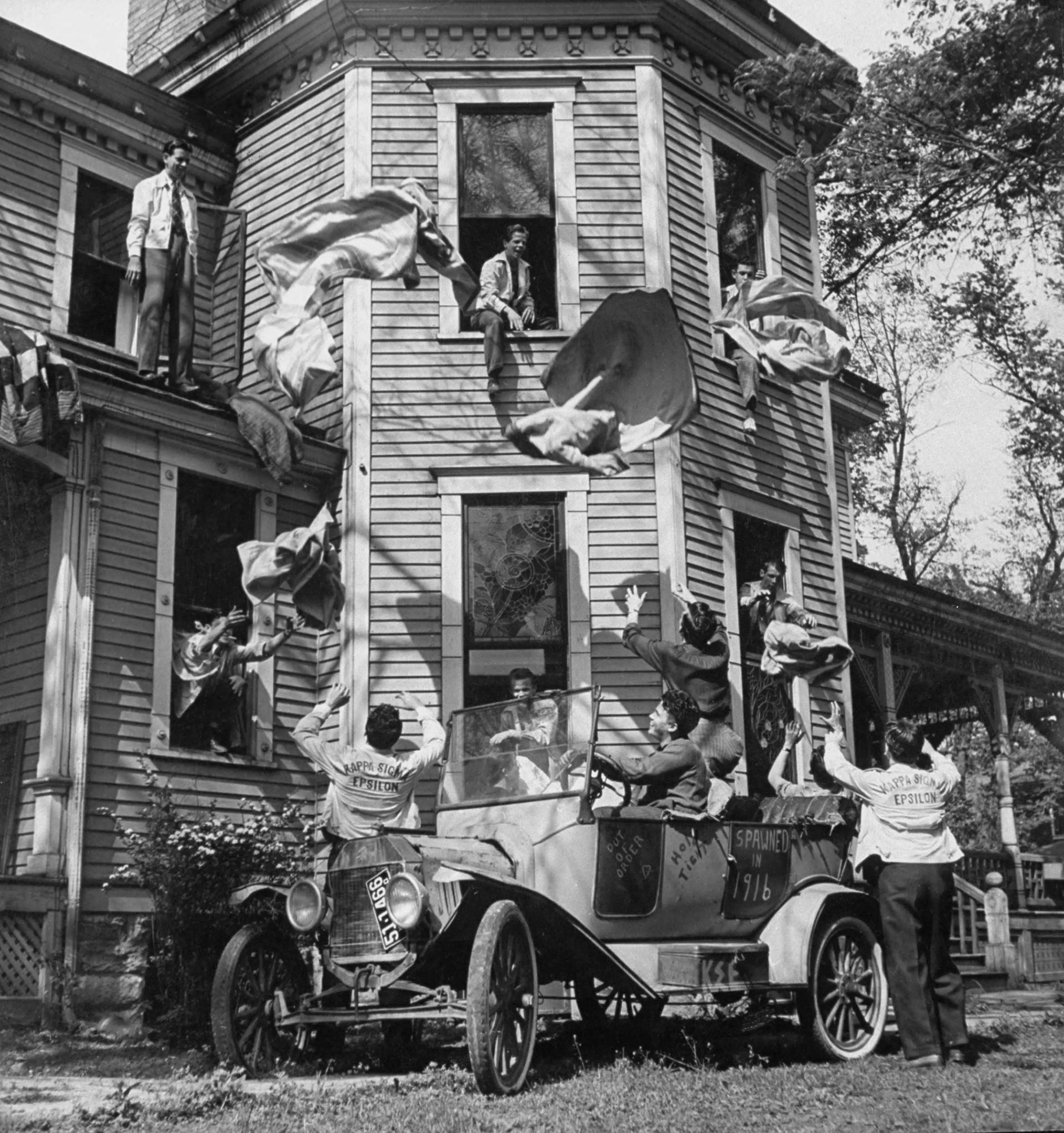 Kappa Sigma Epsilon fraternity members toss blankets out the window of their house in preparation for a spring "blanket party" under the stars at Kansas State Teacher's College. Originally published in the May 26, 1941, issue of LIFE.
