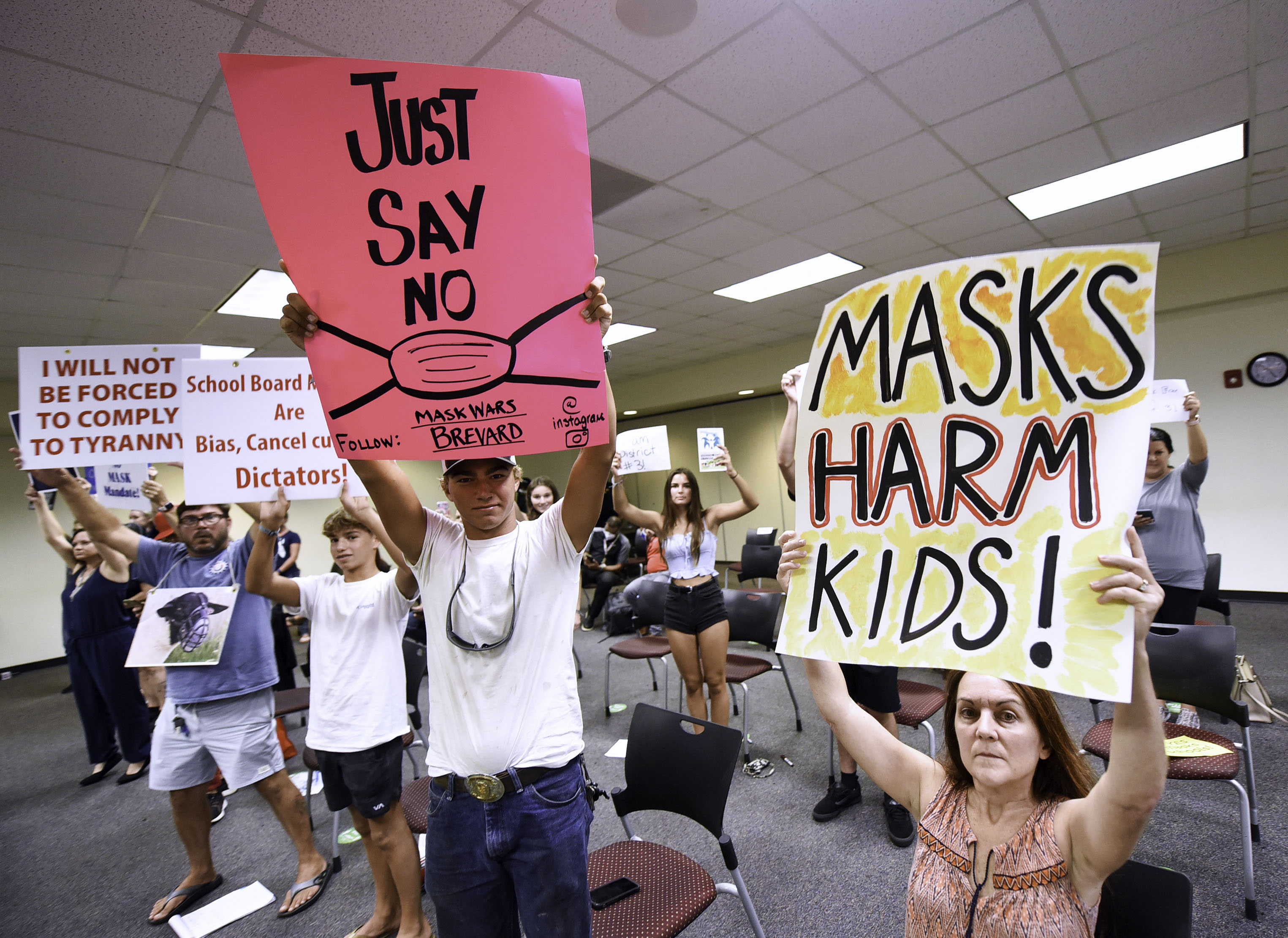 People demonstrate with placards at an emergency meeting of