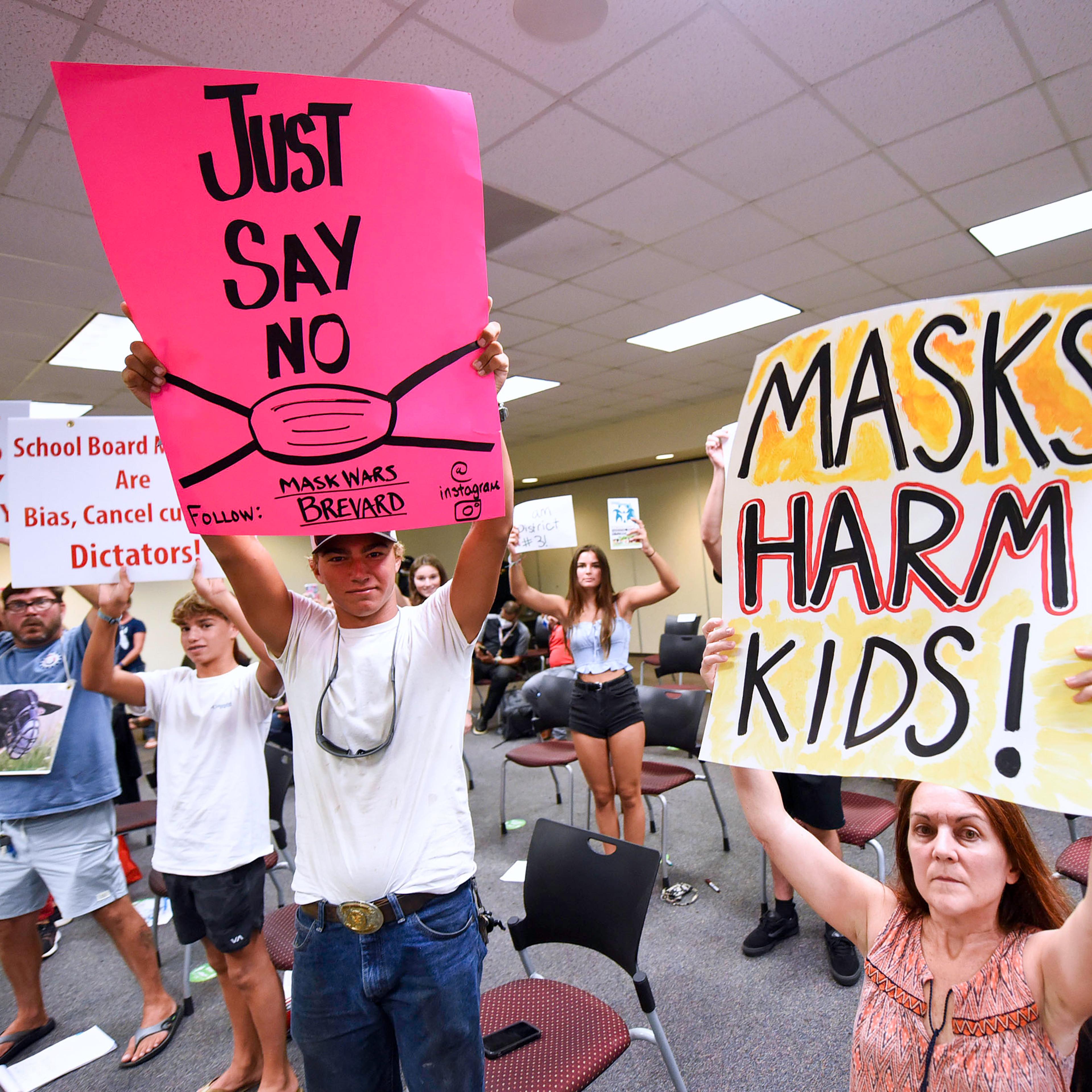 People demonstrate with placards at an emergency meeting of