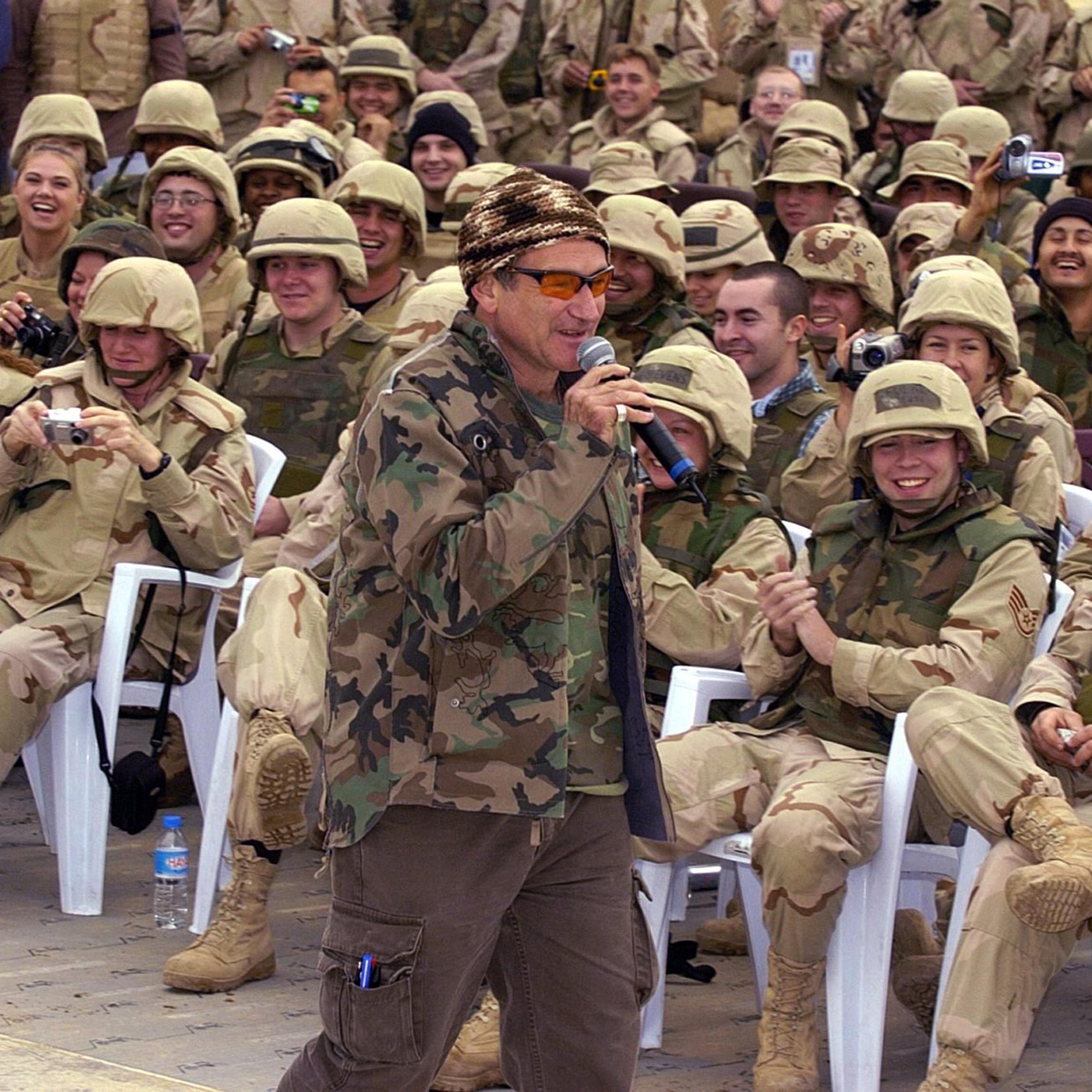 Robin Williams wears a camouflage jacket while entertaining a cheering crowd of US troops as part of a United Service Organiztions (USO) Holiday Tour at the International Airport in Baghdad, Dec. 16, 2003.