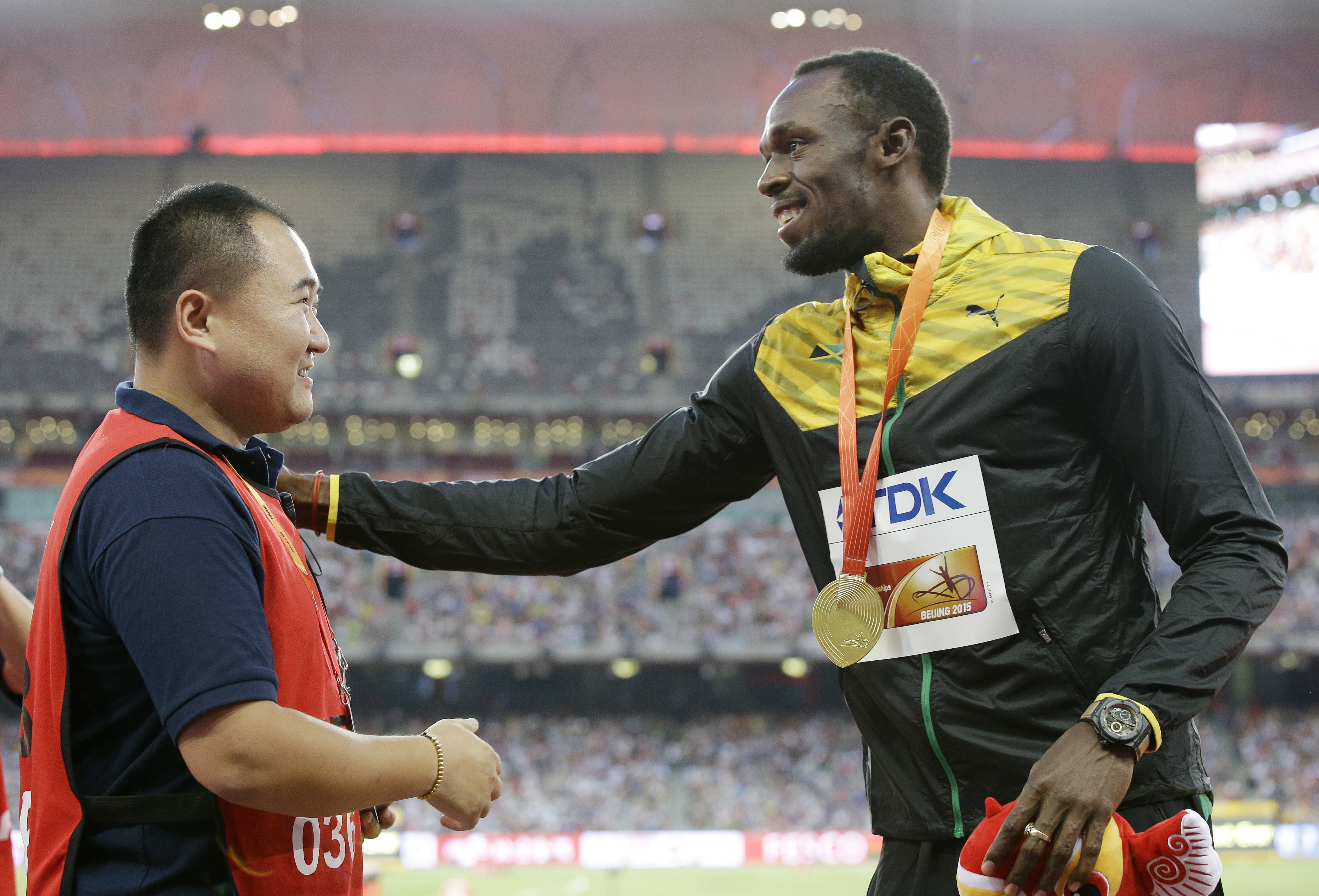 Jamaica's Usain Bolt, left, receives a gift from the cameraman who hit Bolt with a segway after the 200m final on Aug. 27. 