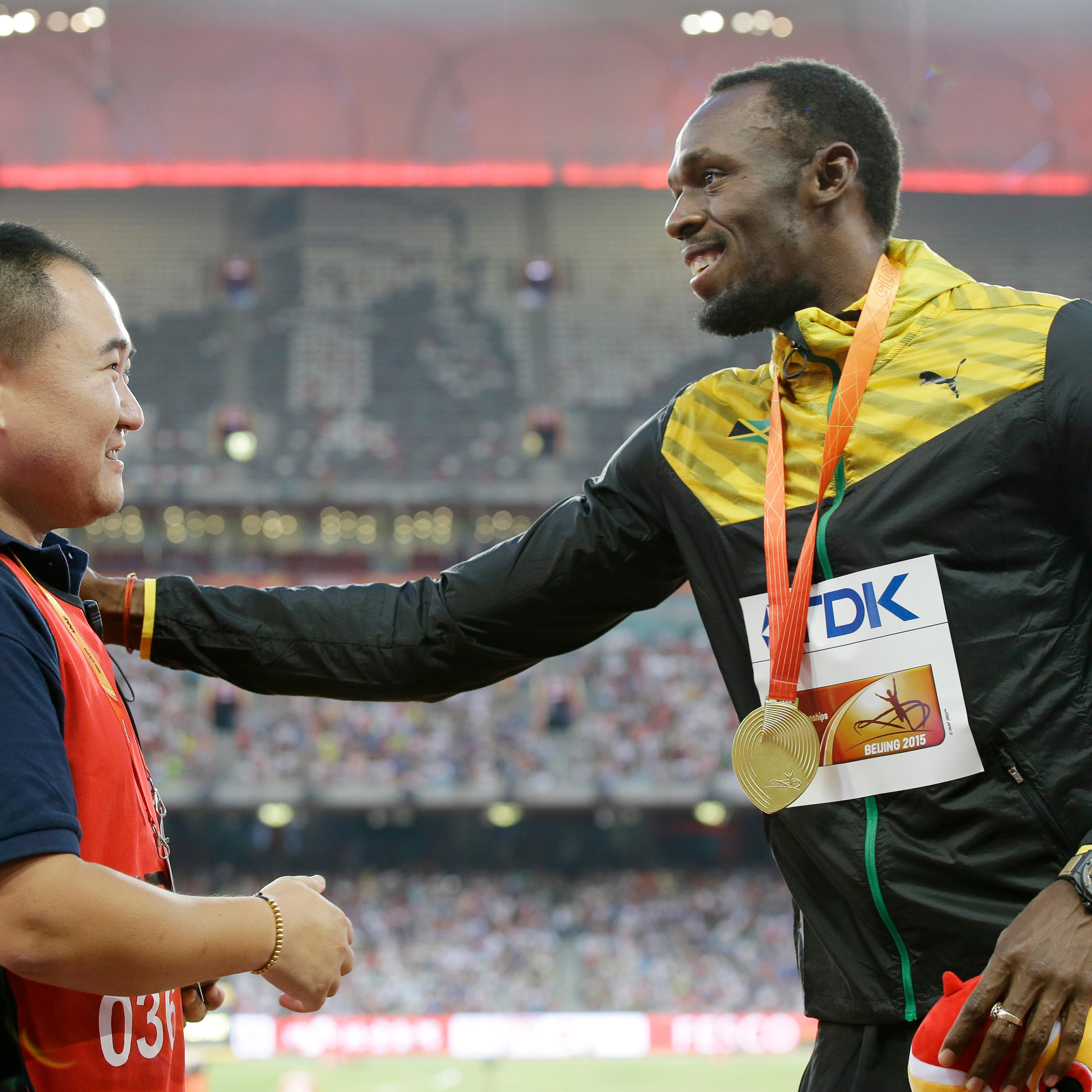 Jamaica's Usain Bolt, left, receives a gift from the cameraman who hit Bolt with a segway after the 200m final on Aug. 27.