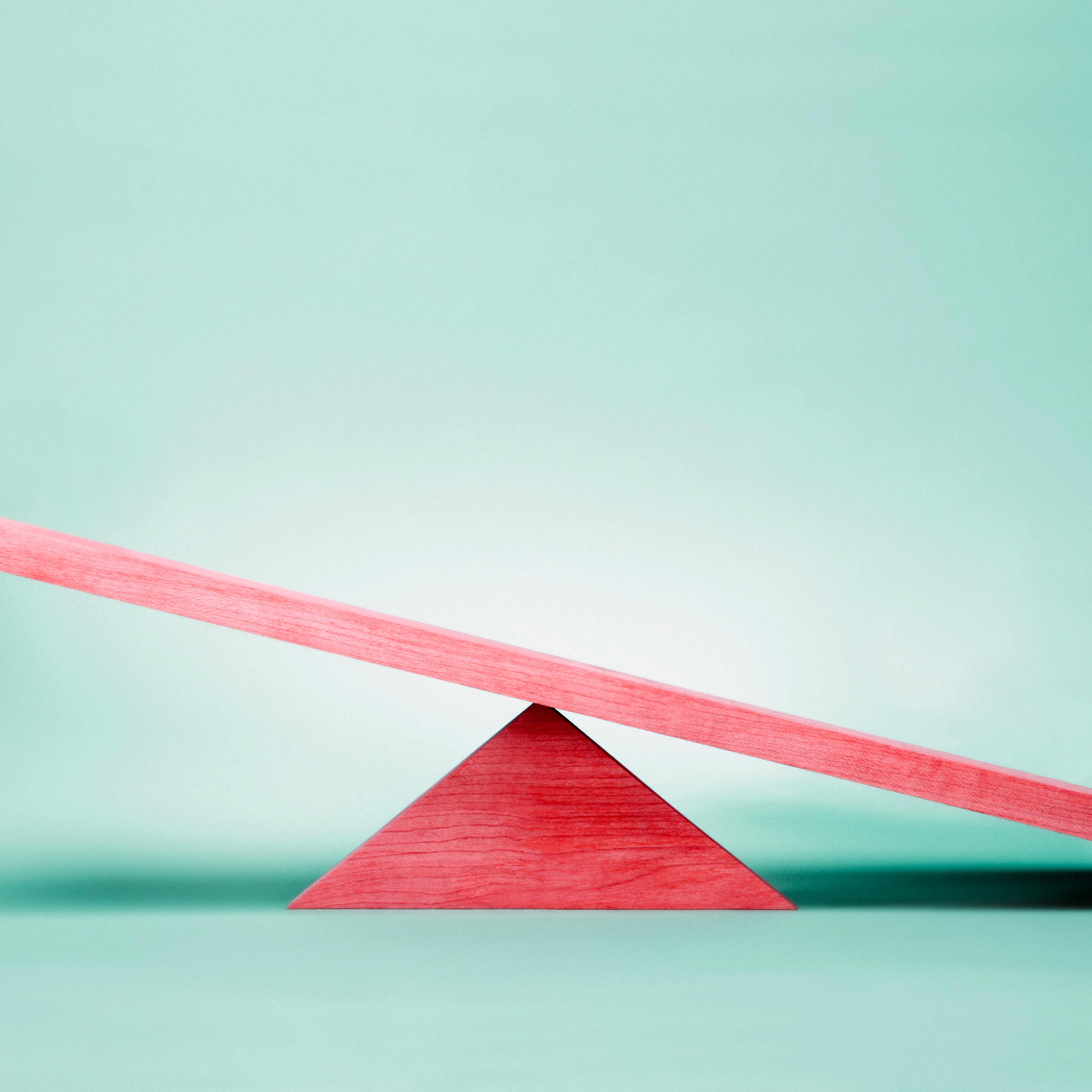 Empty red seesaw on green background