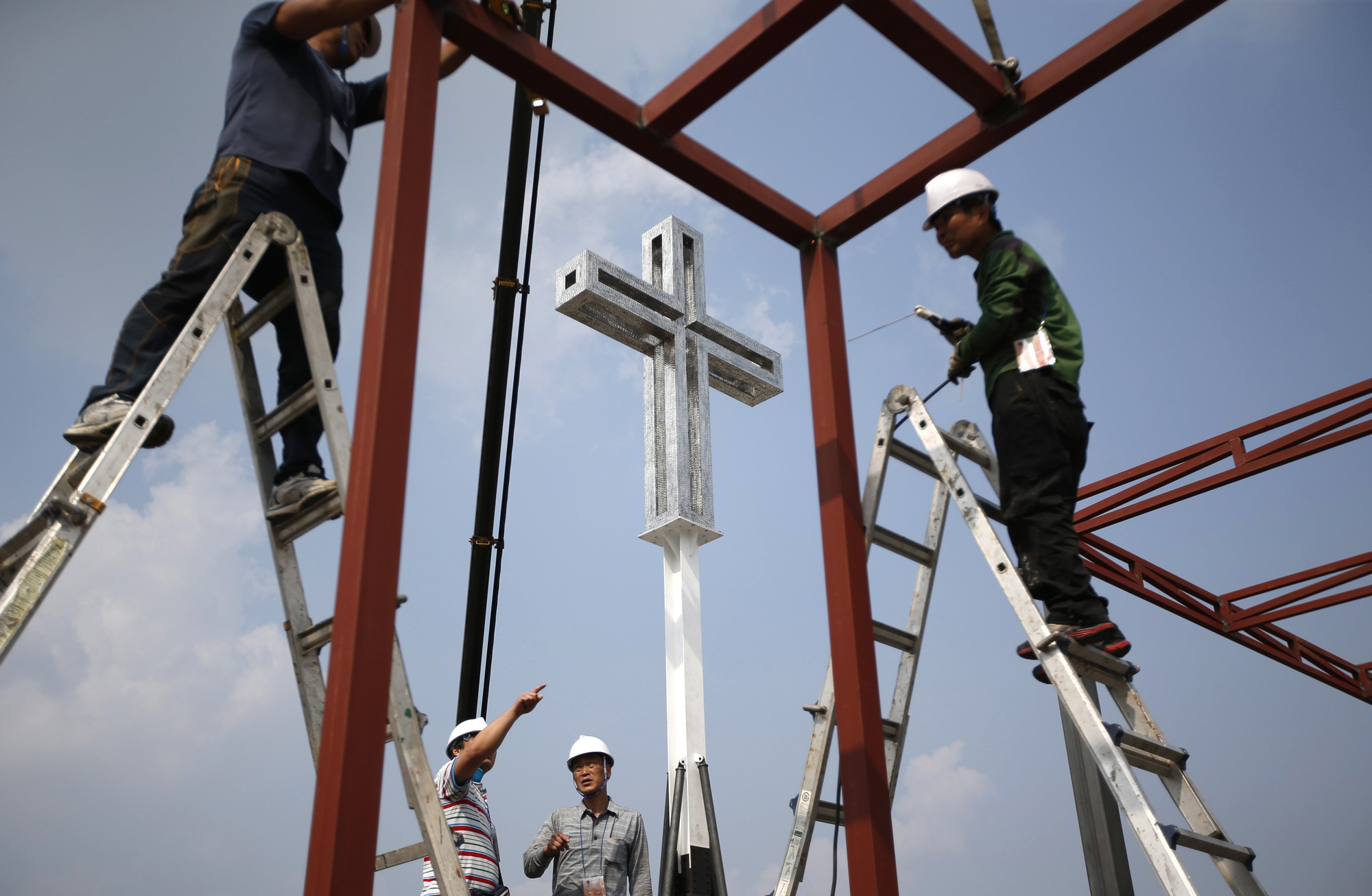 A giant cross is seen as labourers work to assemble a stage in front of Gwanghwamun, ahead of Pope Francis' visit in central Seoul