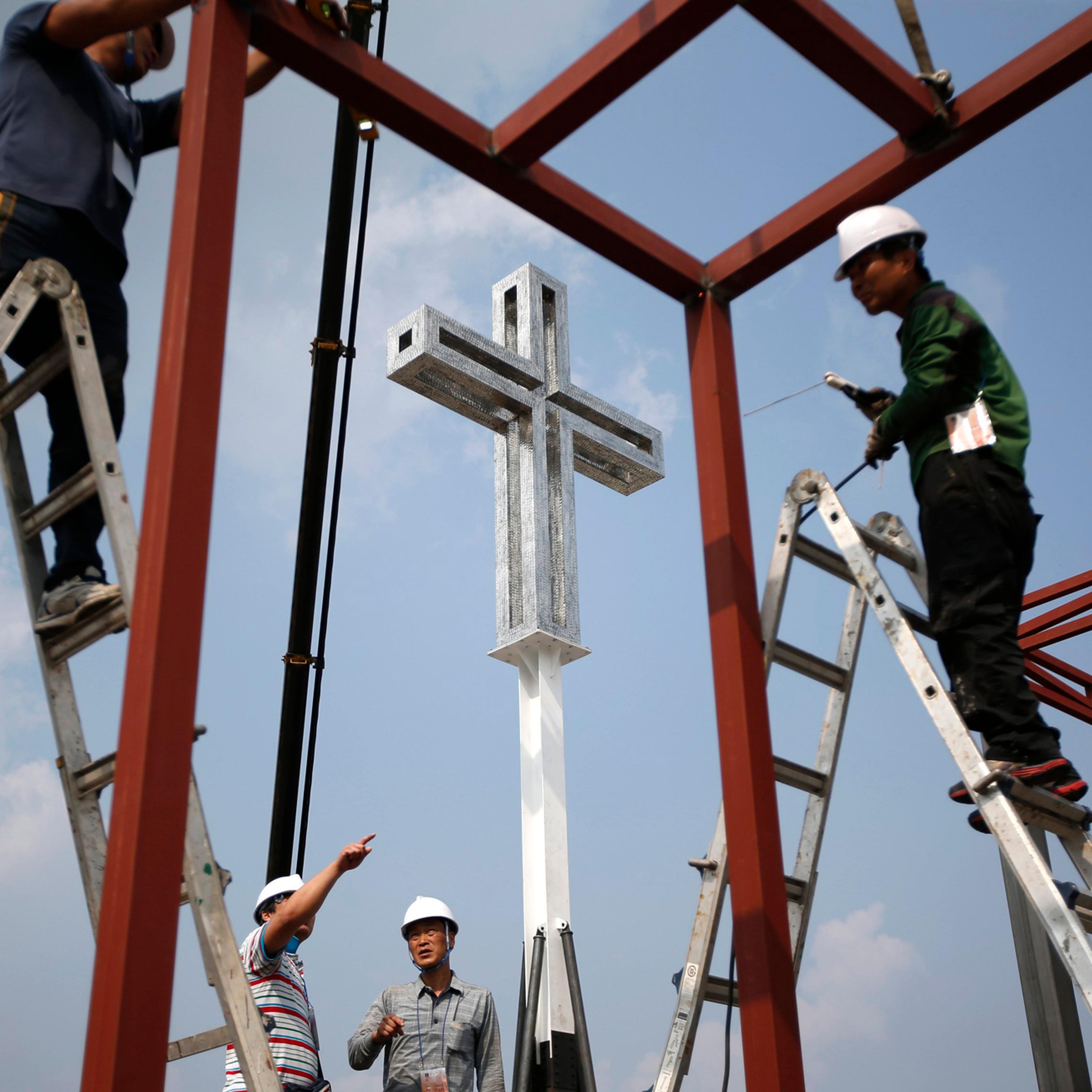 A giant cross is seen as labourers work to assemble a stage in front of Gwanghwamun, ahead of Pope Francis' visit in central Seoul