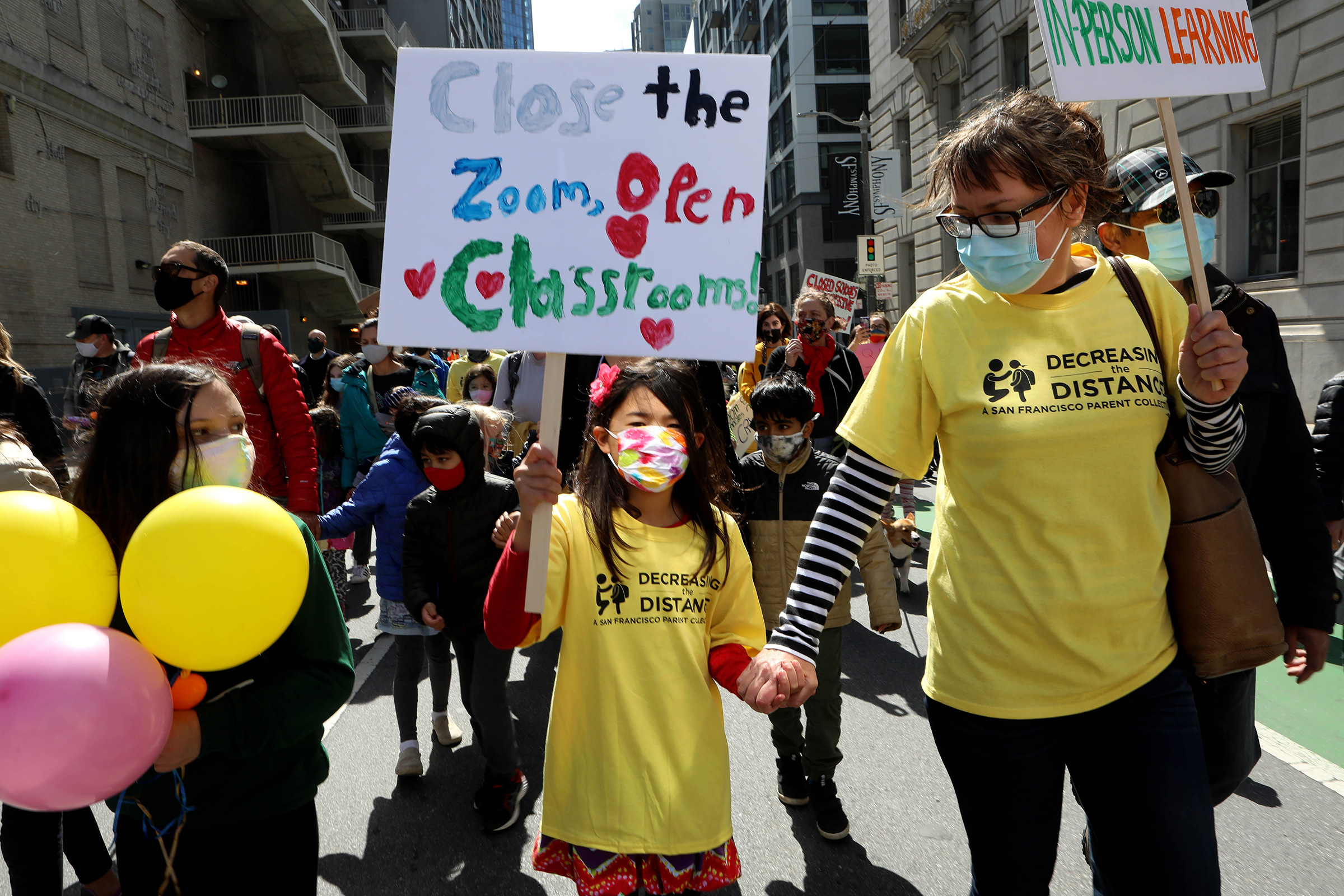 Kristina Leng, 9, marches to the Civic Center with her mother Monika Leng, and father Rodney Leng during the Families Rally to Demand Schools Fully Reopen event in San Francisco, on March 13, 2021.dent, marches to the Civic Center as she holds hands with