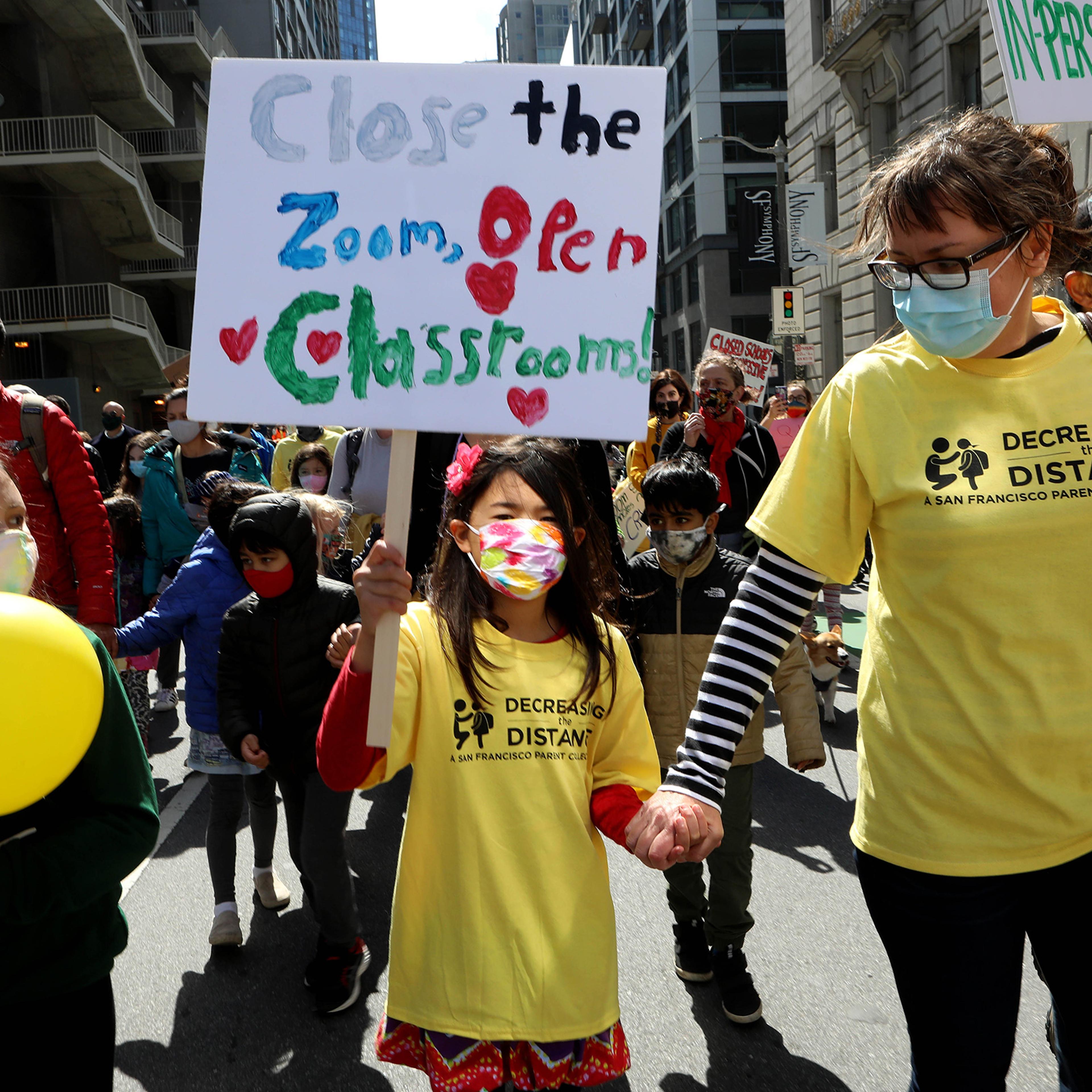 Kristina Leng, 9, marches to the Civic Center with her mother Monika Leng, and father Rodney Leng during the Families Rally to Demand Schools Fully Reopen event in San Francisco, on March 13, 2021.dent, marches to the Civic Center as she holds hands with