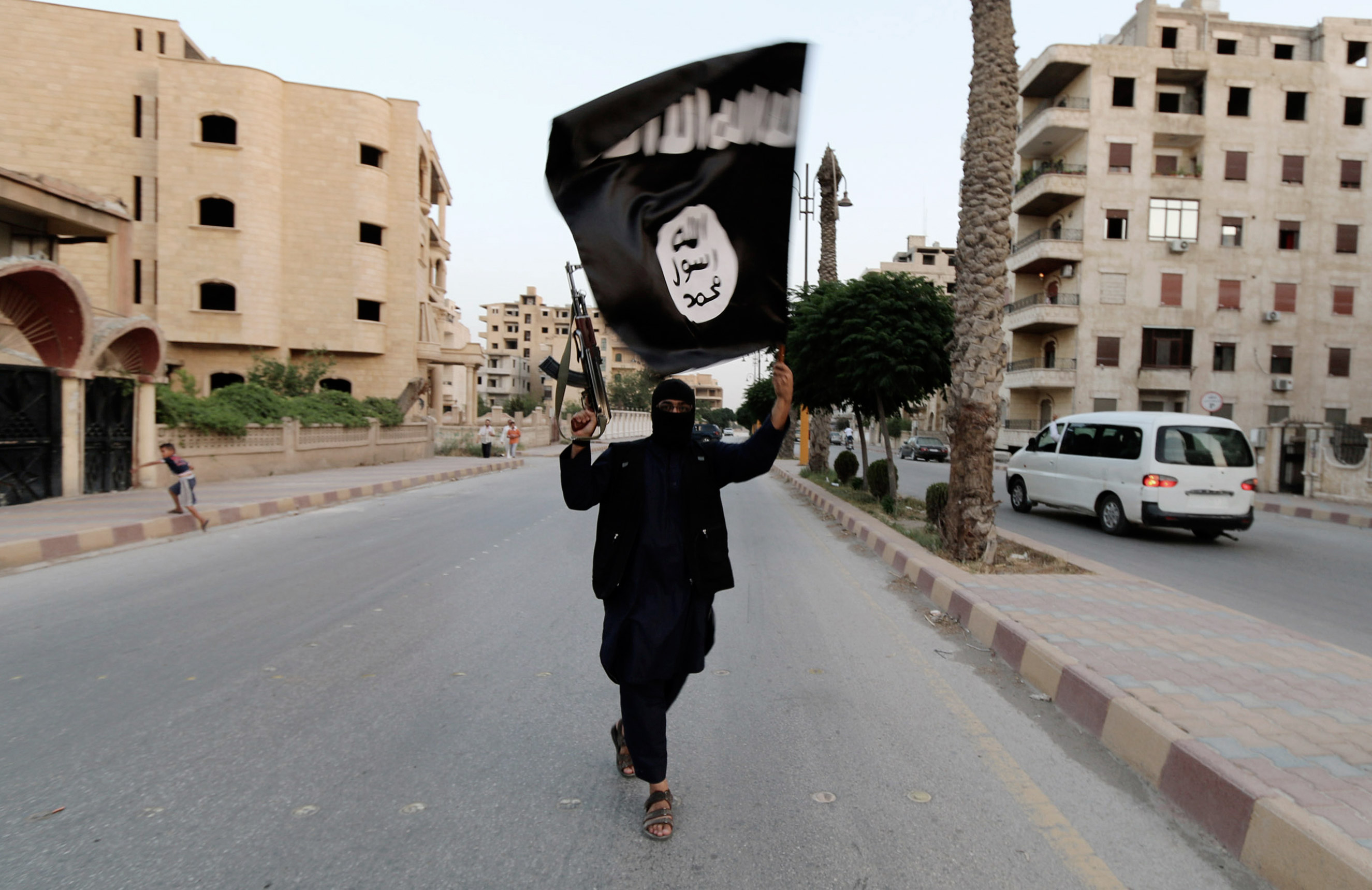 A member loyal to the Islamic State in Iraq and the Levant (ISIL) waves an ISIL flag in Raqqa on June 29, 2014.