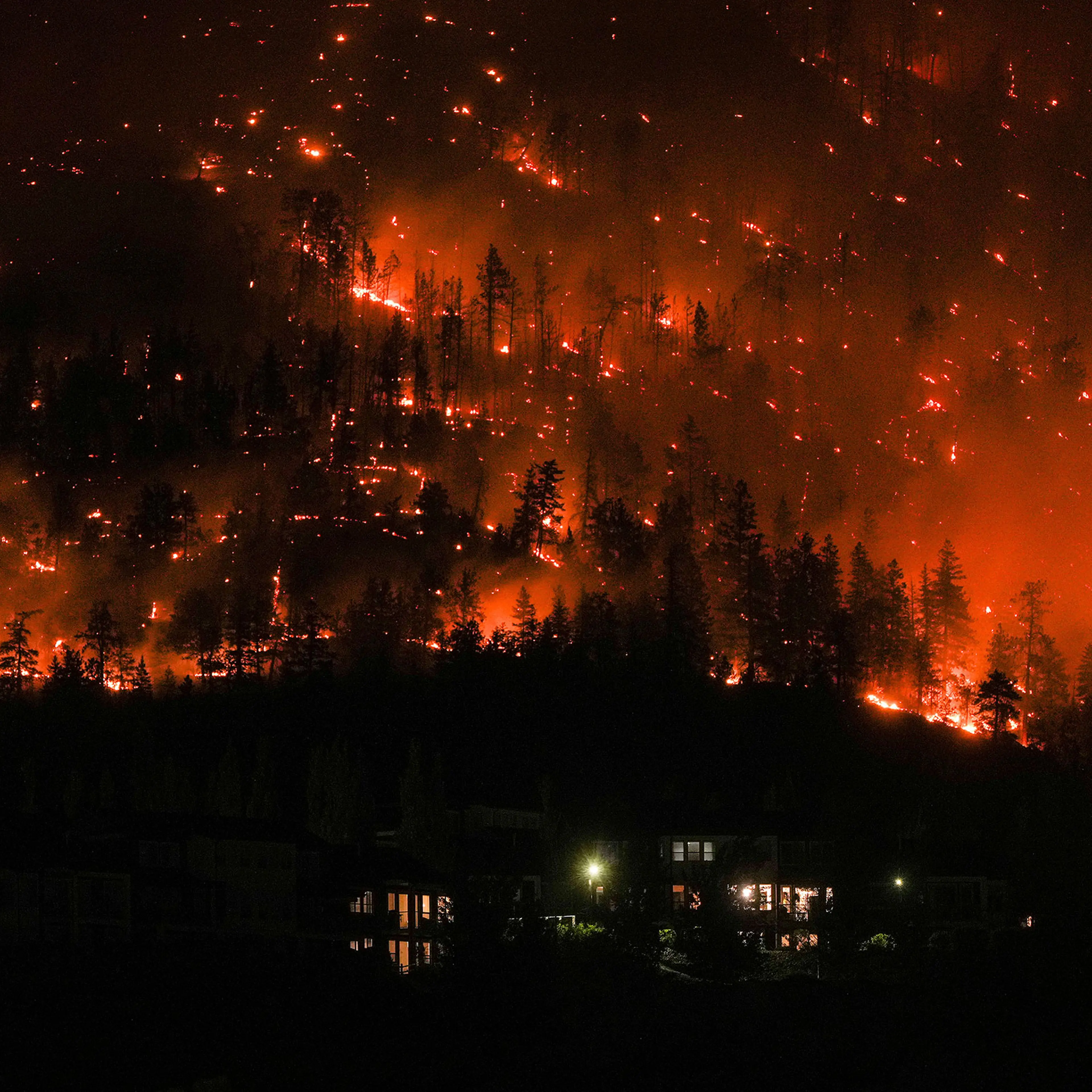 The McDougall Creek wildfire burns on the mountainside above houses in West Kelowna, B.C., on Aug. 18.