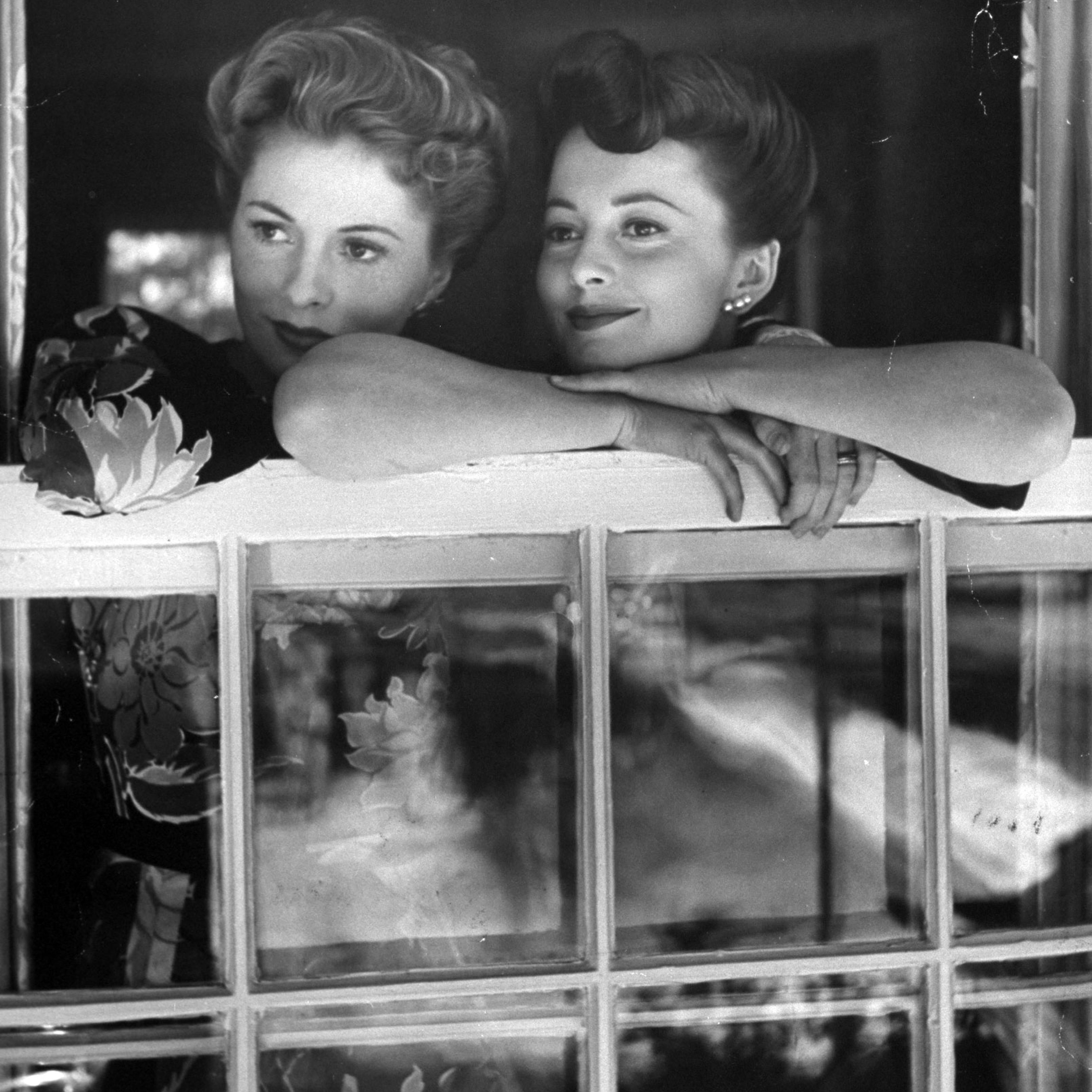 As successful movie stars, Joan (left) and Olivia make one of their rare appearances together in a window at Joan's home. This year they were winner and runner-up, respectively, for the Academy Award.