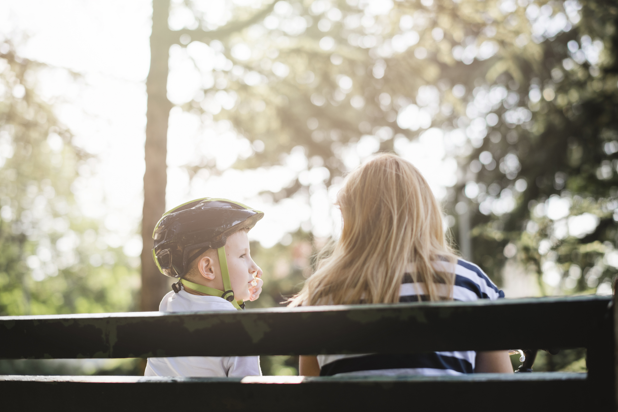 Mother and son sitting on a bench in the park and talking