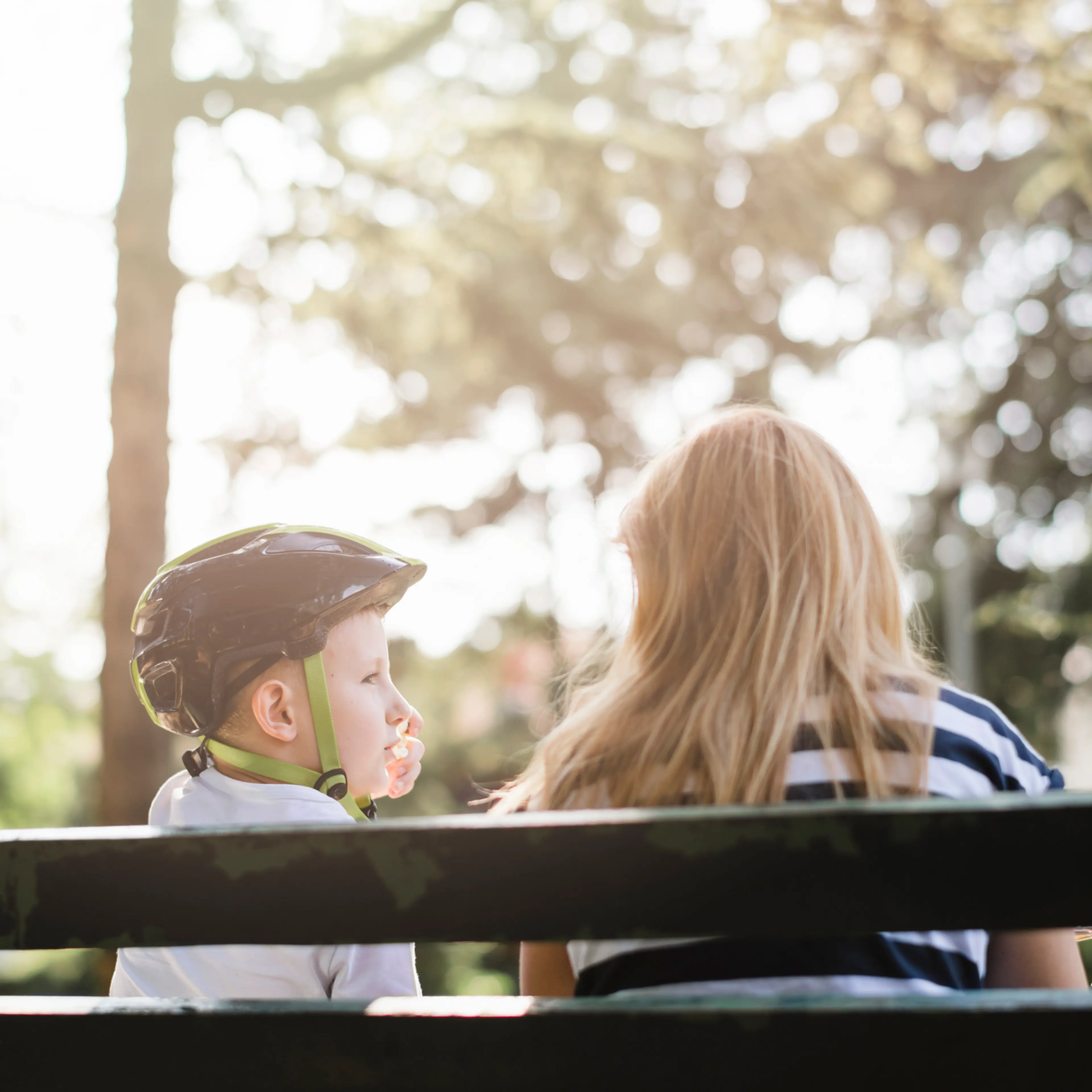 Mother and son sitting on a bench in the park and talking