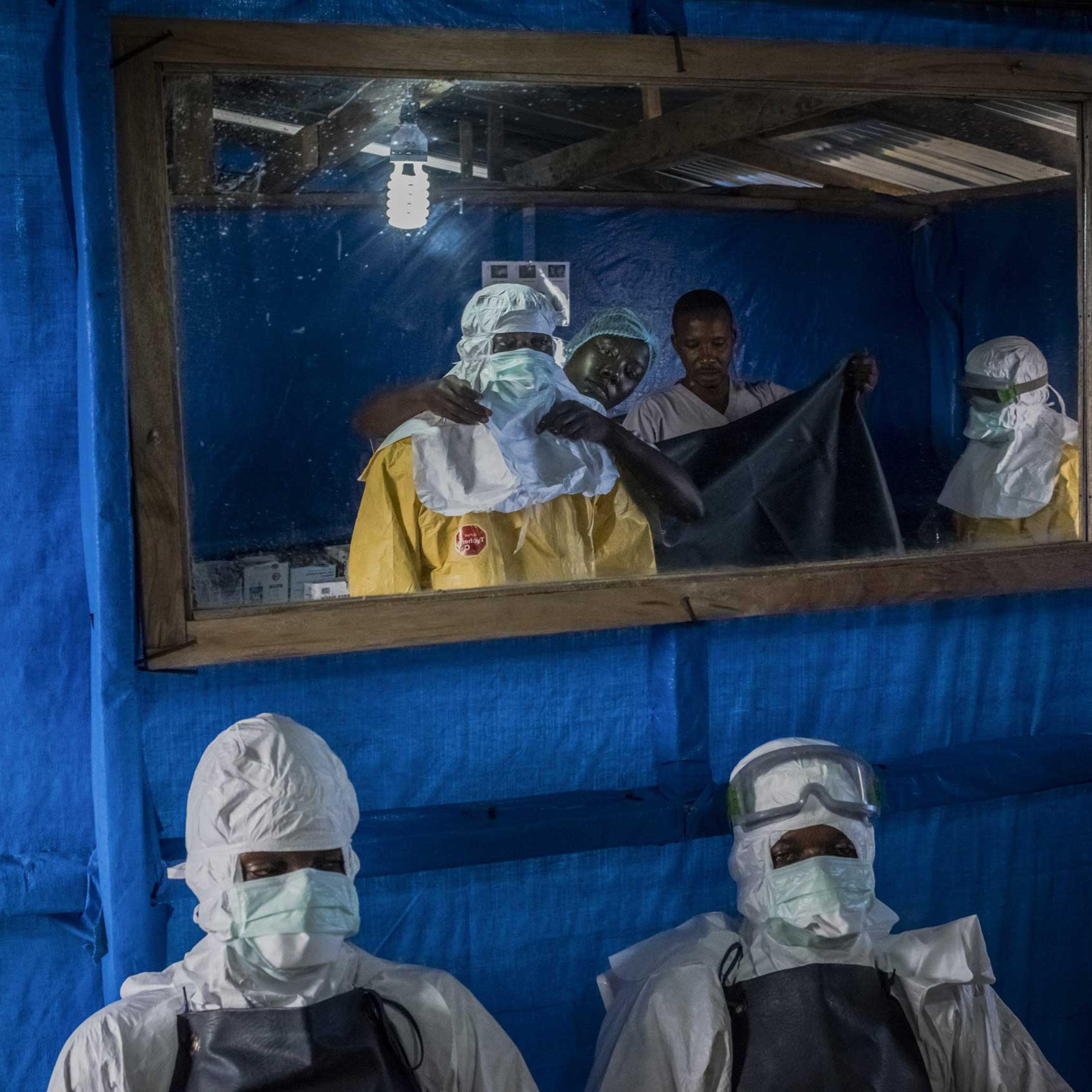 Health workers receive assistance with putting on their protective gear before entering the high-risk zone at the Bong County Ebola Treatment Unit near Gbarnga in rural Bong County, Liberia, Oct. 5, 2014.