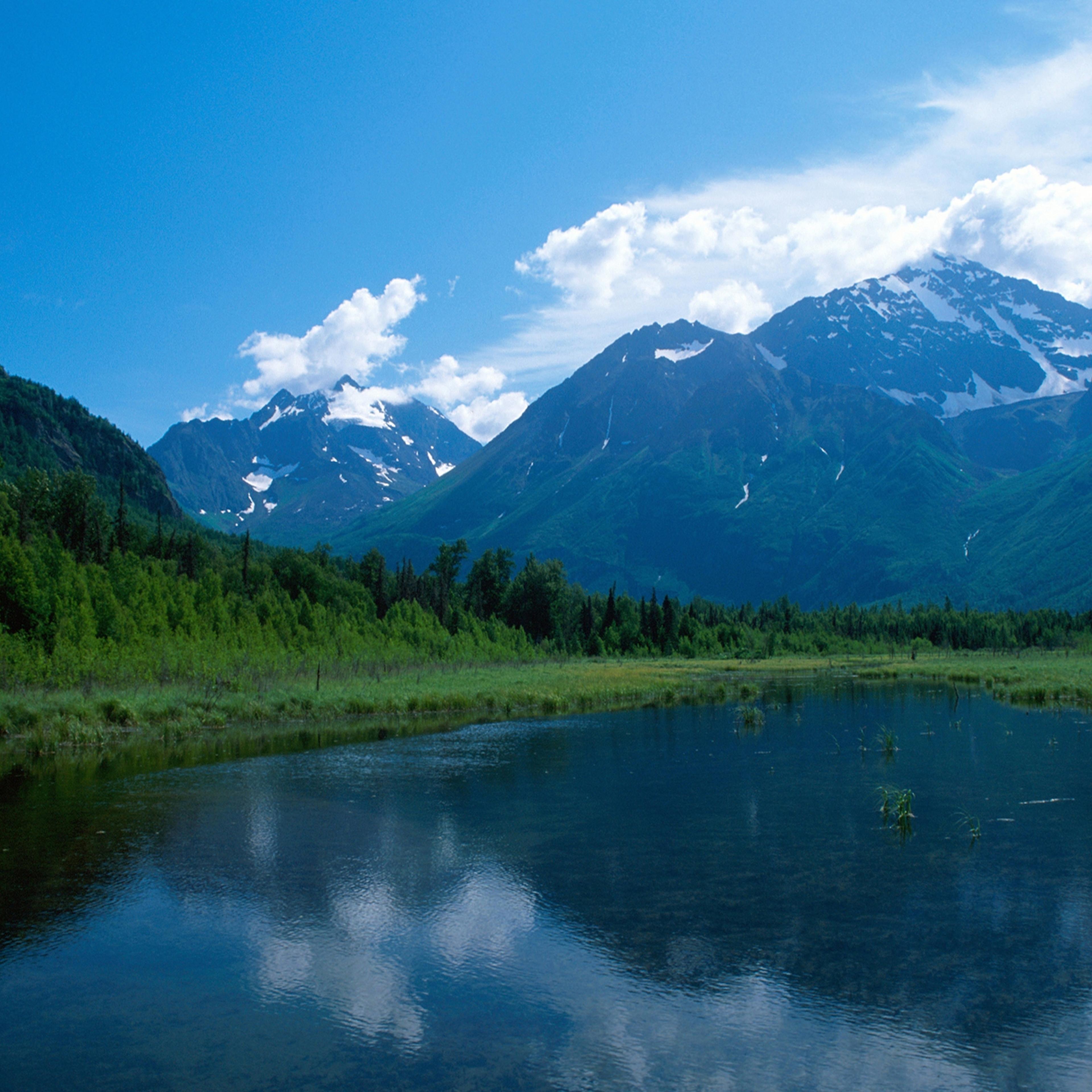 Snow covers portions of Alaskan mountain range in the distance, as seen from across a small body of water, 2014.