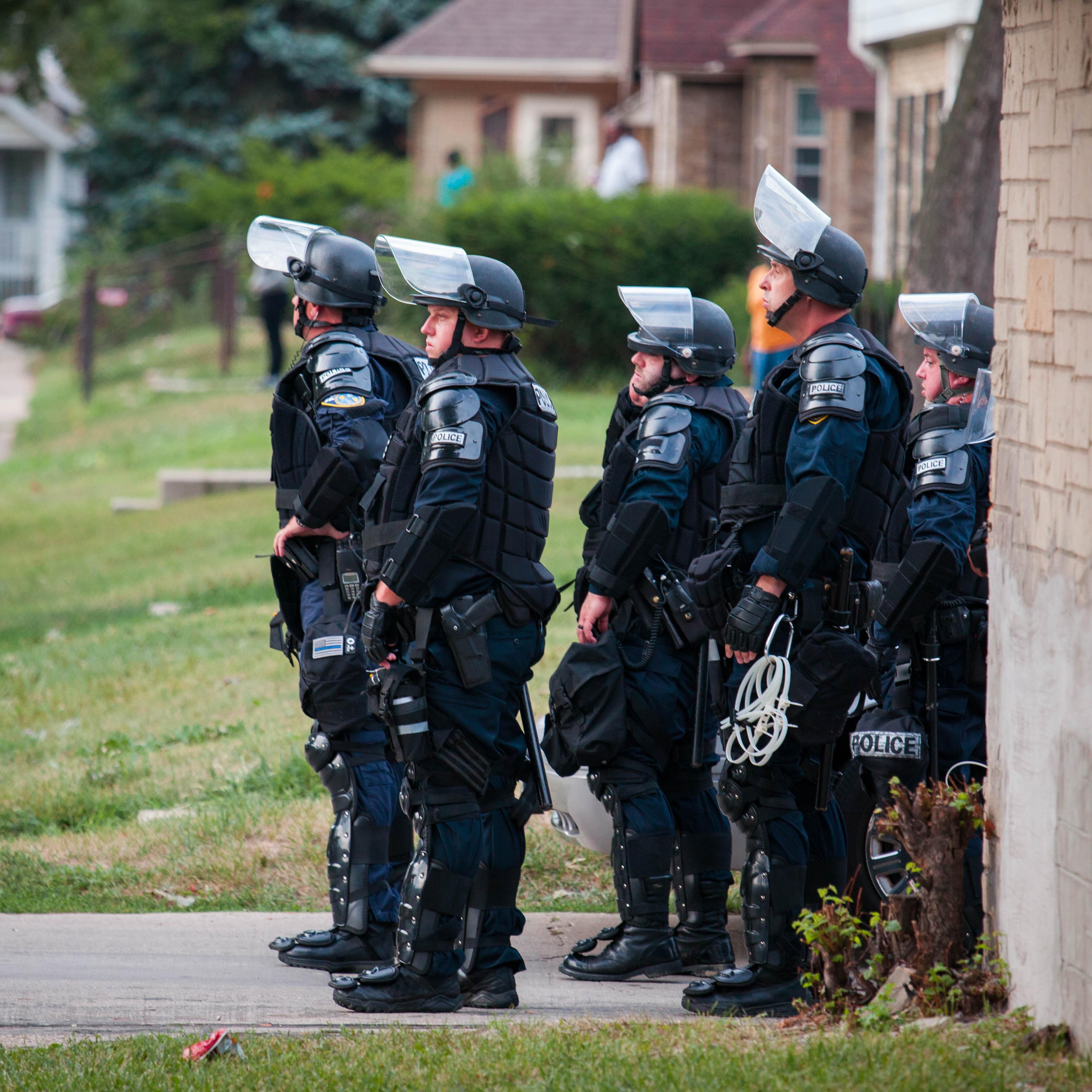 Police in riot gear wait in an alley after a second night of clashes between protestors and police in Milwaukee, Wisc., on Aug. 15, 2016.