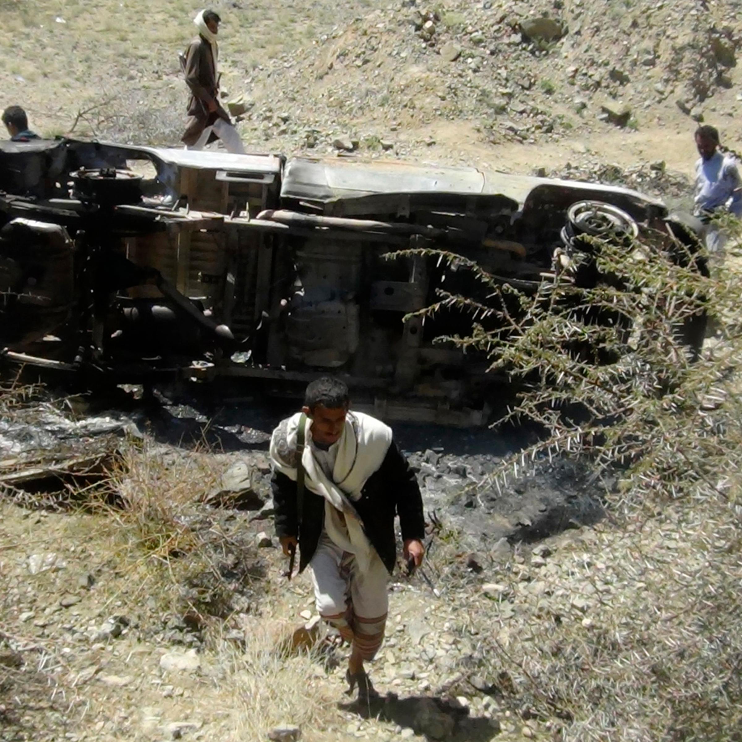 People inspect the wreckage of a car hit by an air strike in the central Yemeni province of al-Bayda