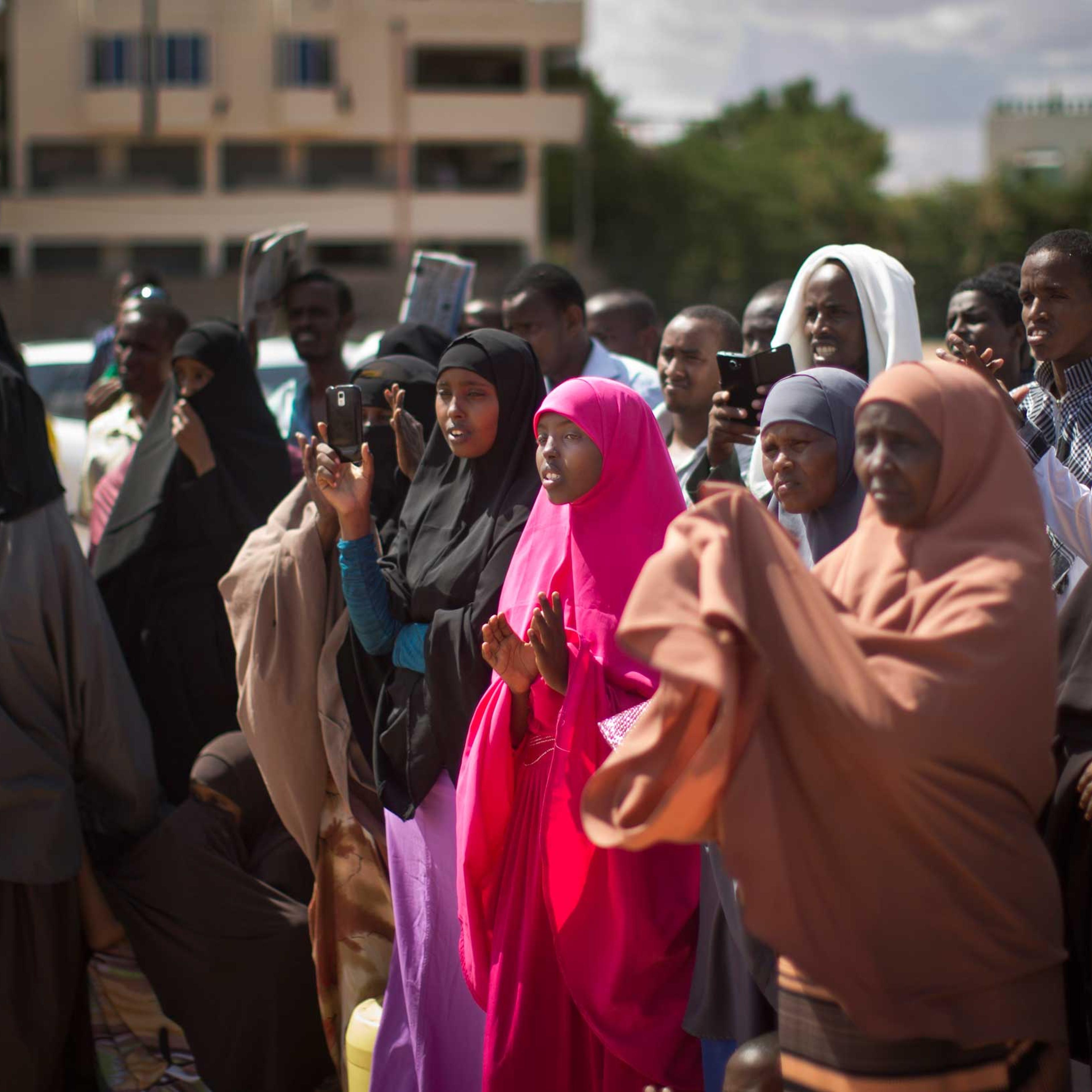 Kenyan Muslim women and men applaud as a women's representative denounces the latest attack by al-Shabab gunmen, at a public meeting in Garissa, Kenya, on Apr. 3, 2015.