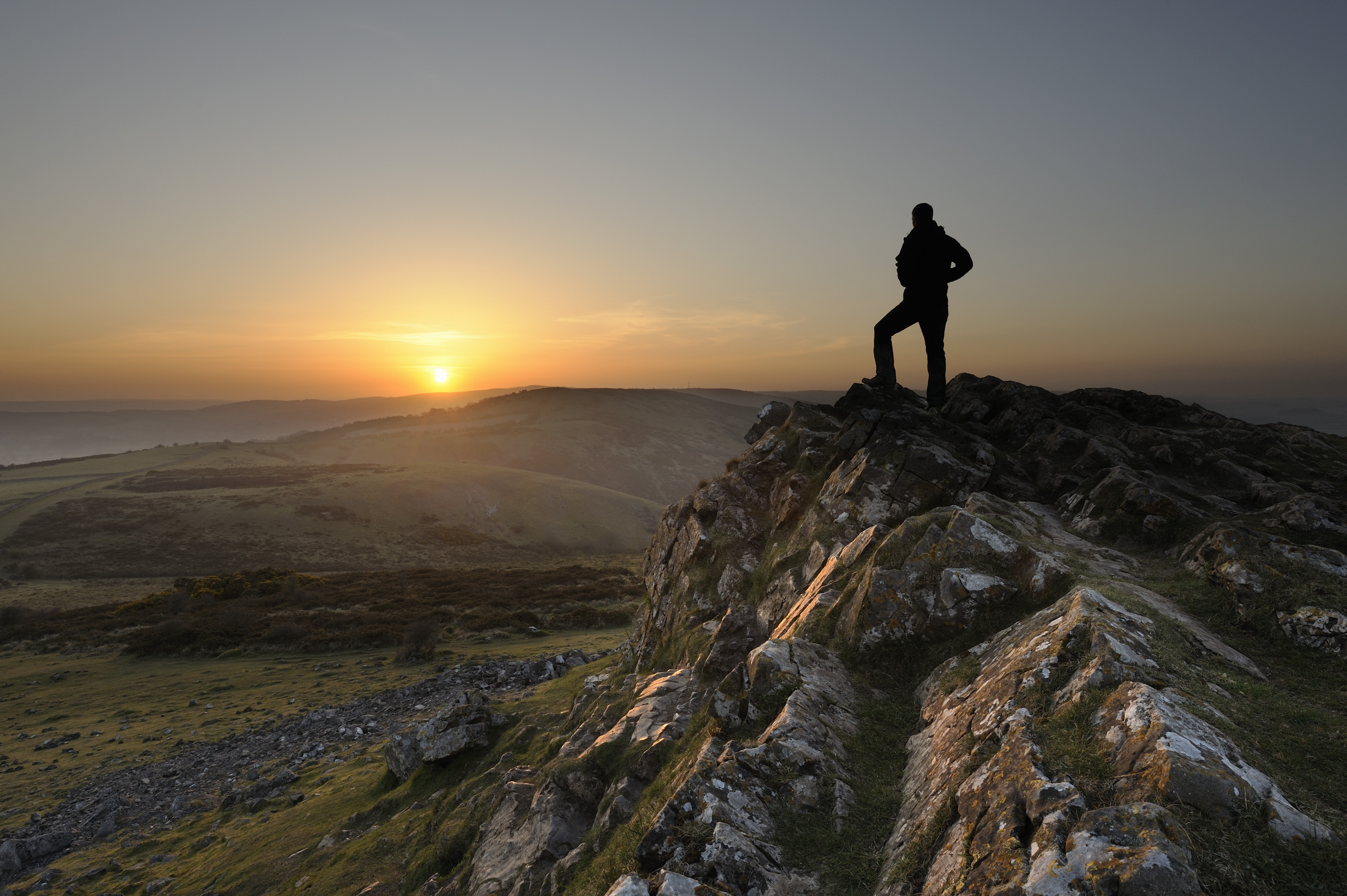 man-standing-mountain-peak-sunset